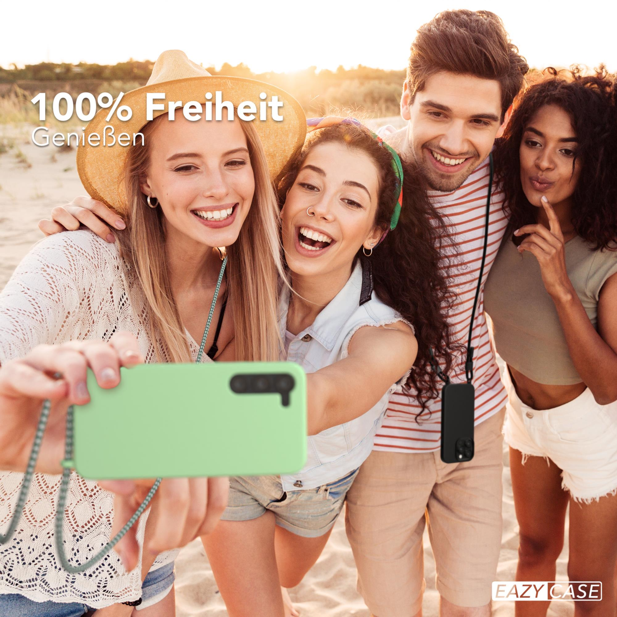 Freundesgruppe macht Selfie am Strand, hält eine grüne Handyhülle.