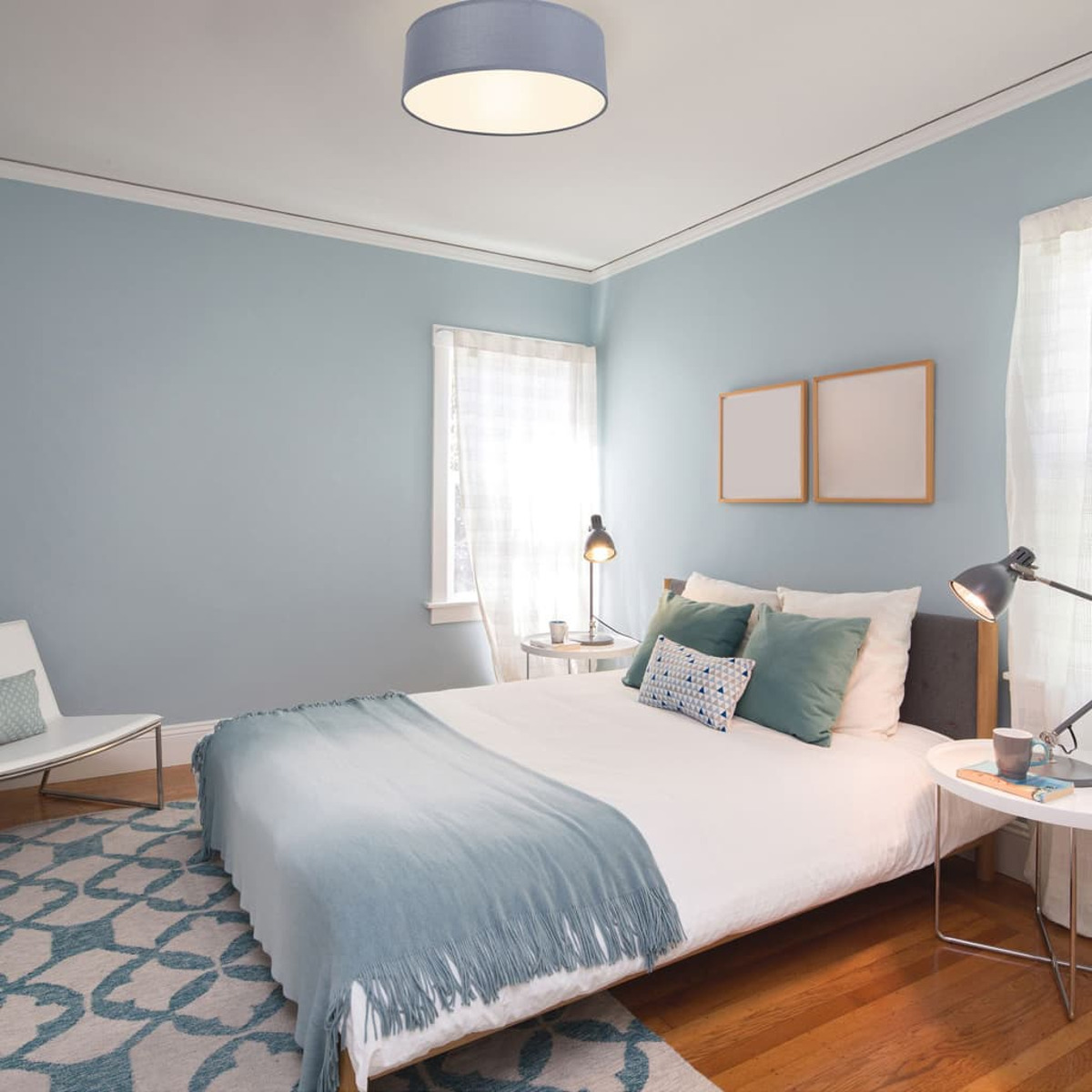 Camera da letto con pareti blu, letto con coperta blu e plafoniera rotonda.
