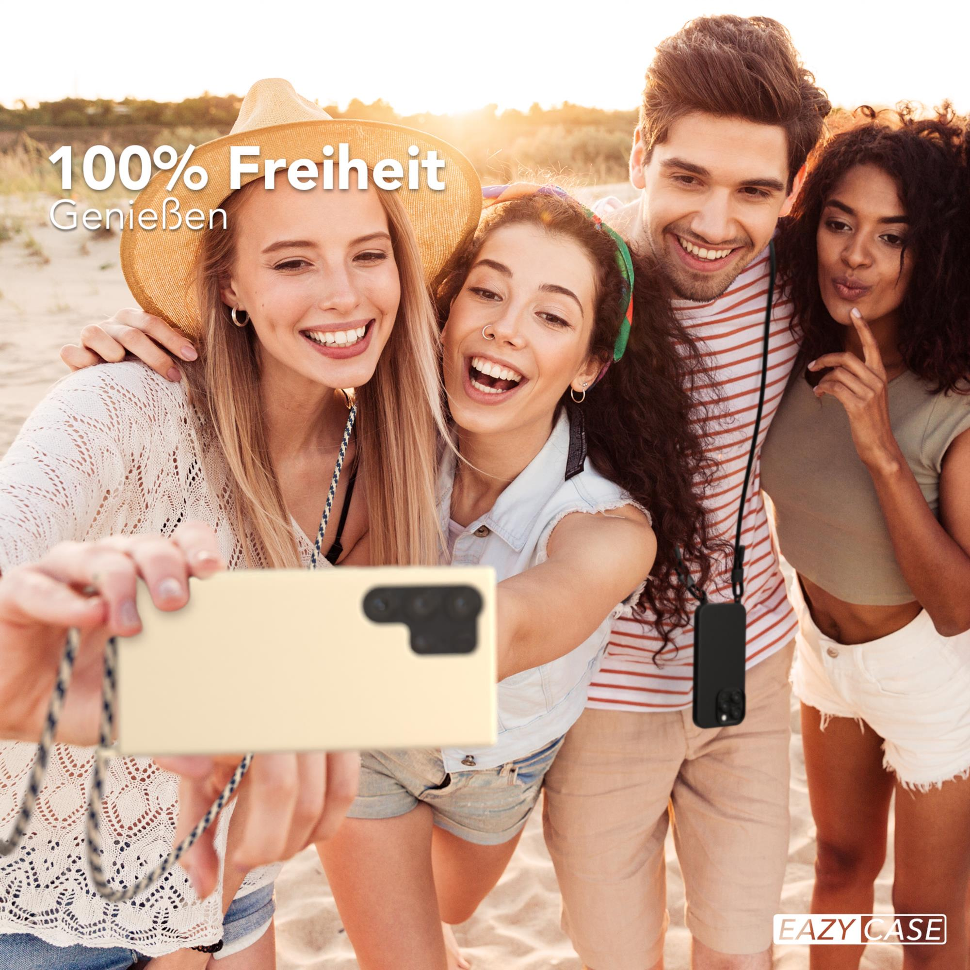 Freundesgruppe macht Selfie am Strand, hält beiges Telefon.