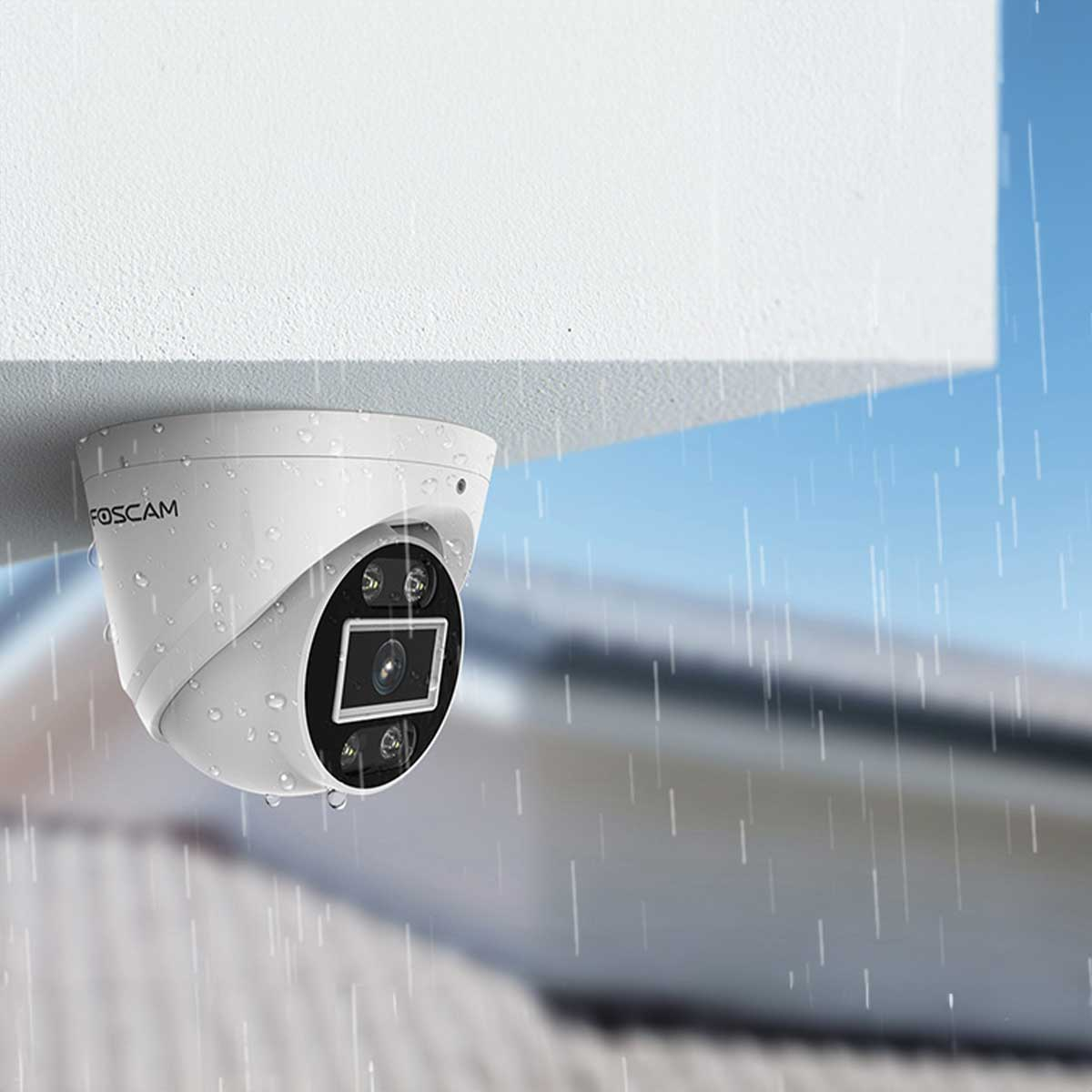 Una cámara de seguridad blanca está montada debajo de una superficie blanca, está lloviendo. La cámara tiene un anillo negro alrededor de la lente.