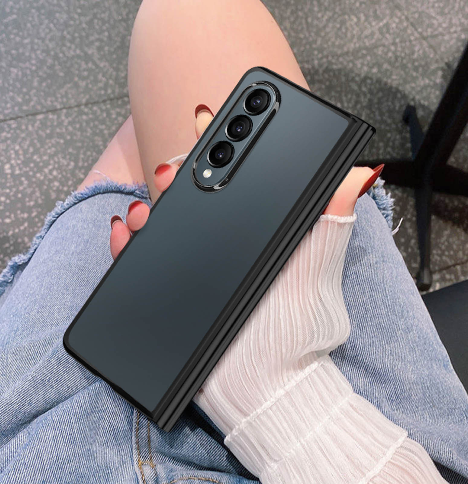 Faltbares Telefon in der Hand, geschlossen, mit drei Kameras, mit Jeans-Hintergrund.