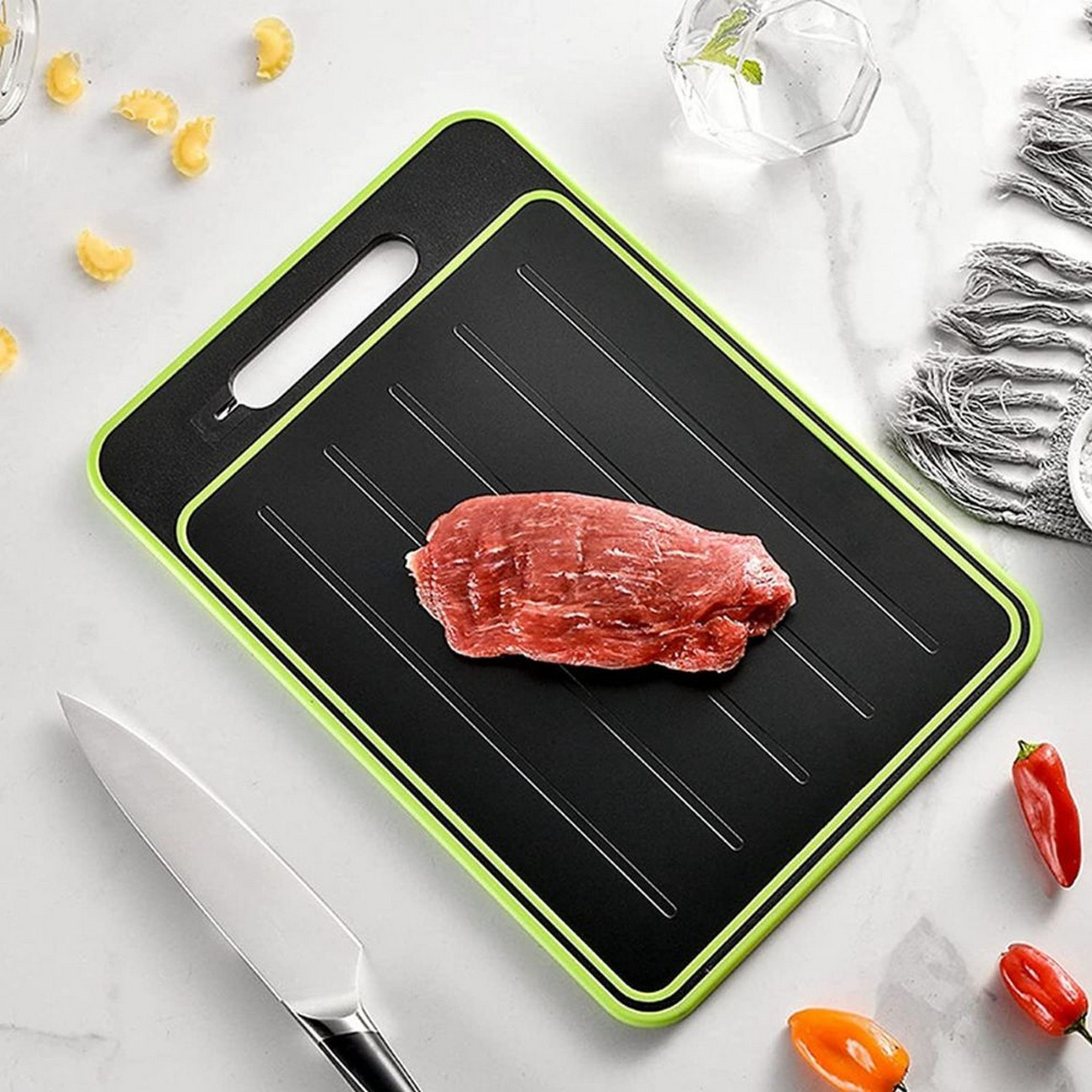 Una tabla de cortar con carne cruda y un cuchillo, rodeada de pimientos y otros elementos.