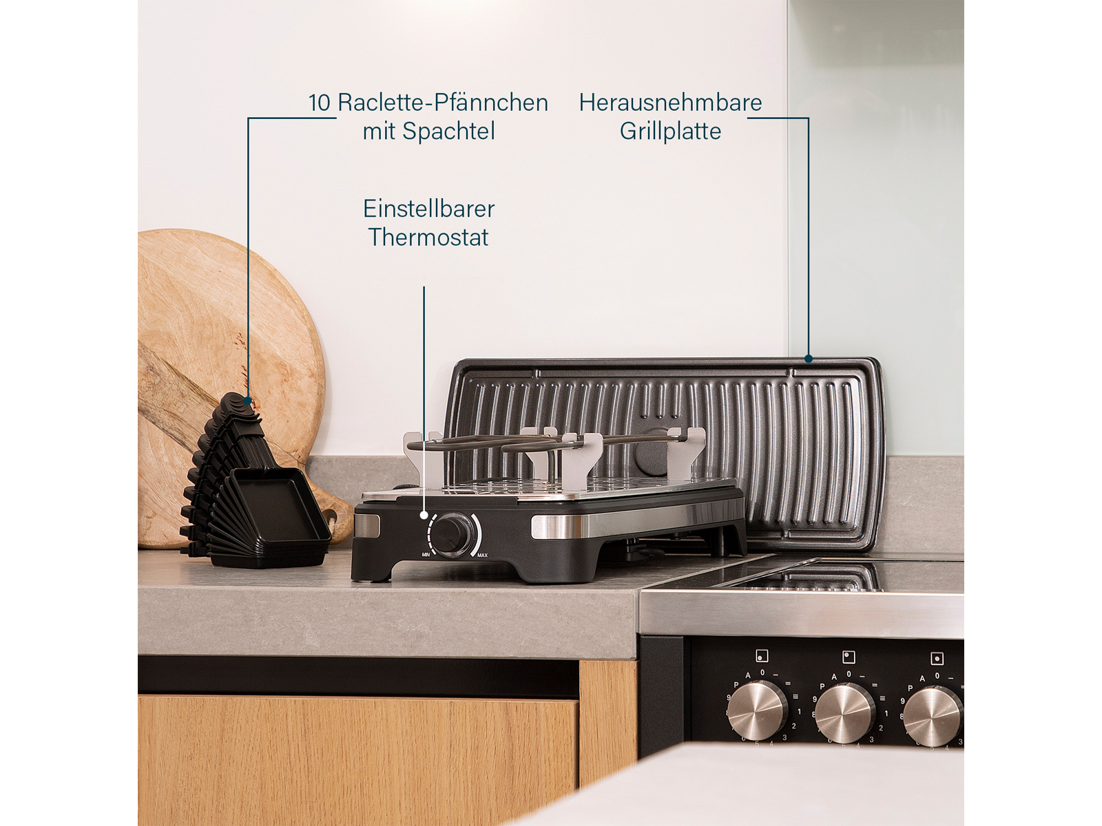 Tischgrill mit beschrifteten Komponenten: Thermostat, Grillplatte und Raclette-Pfännchen. Graue Steinoberfläche.