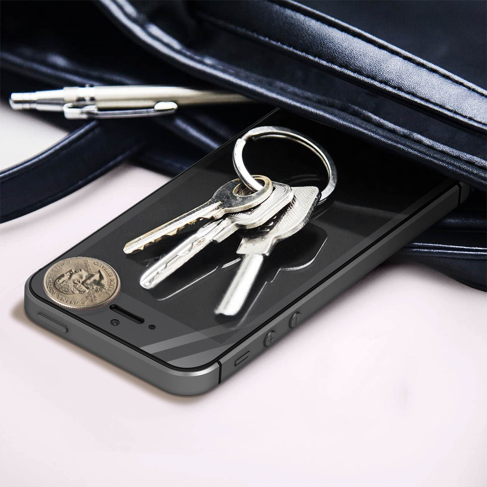 Un smartphone avec des clés et une pièce de monnaie dans un sac noir. Le téléphone est sombre avec un écran noir.