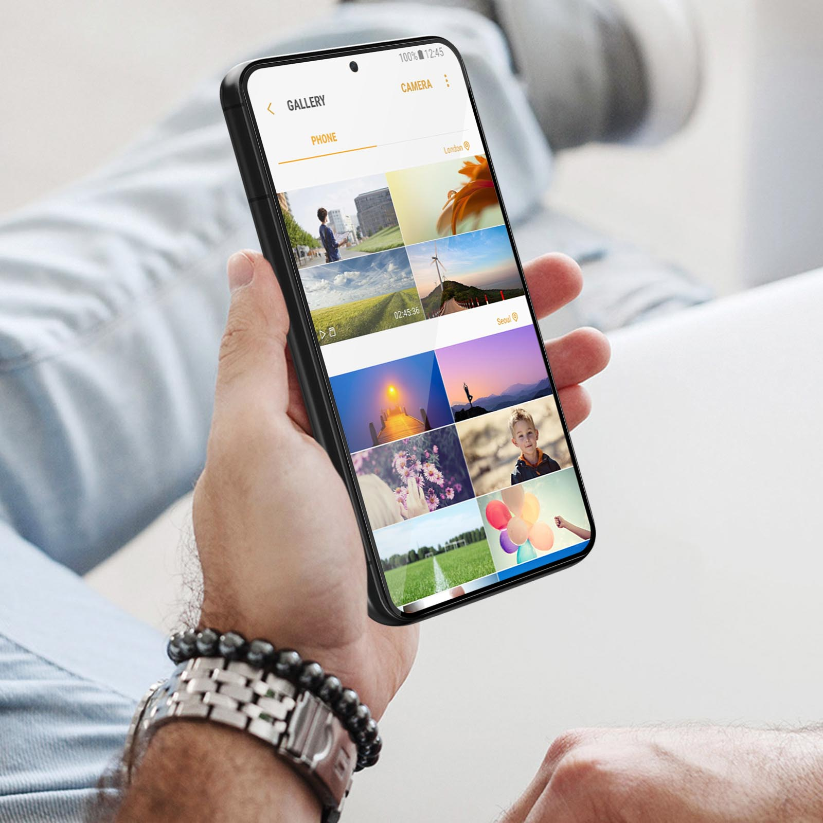 Osoba trzyma telefon wyświetlający galerię zdjęć. Nadgarstek z bransoletką w kadrze.