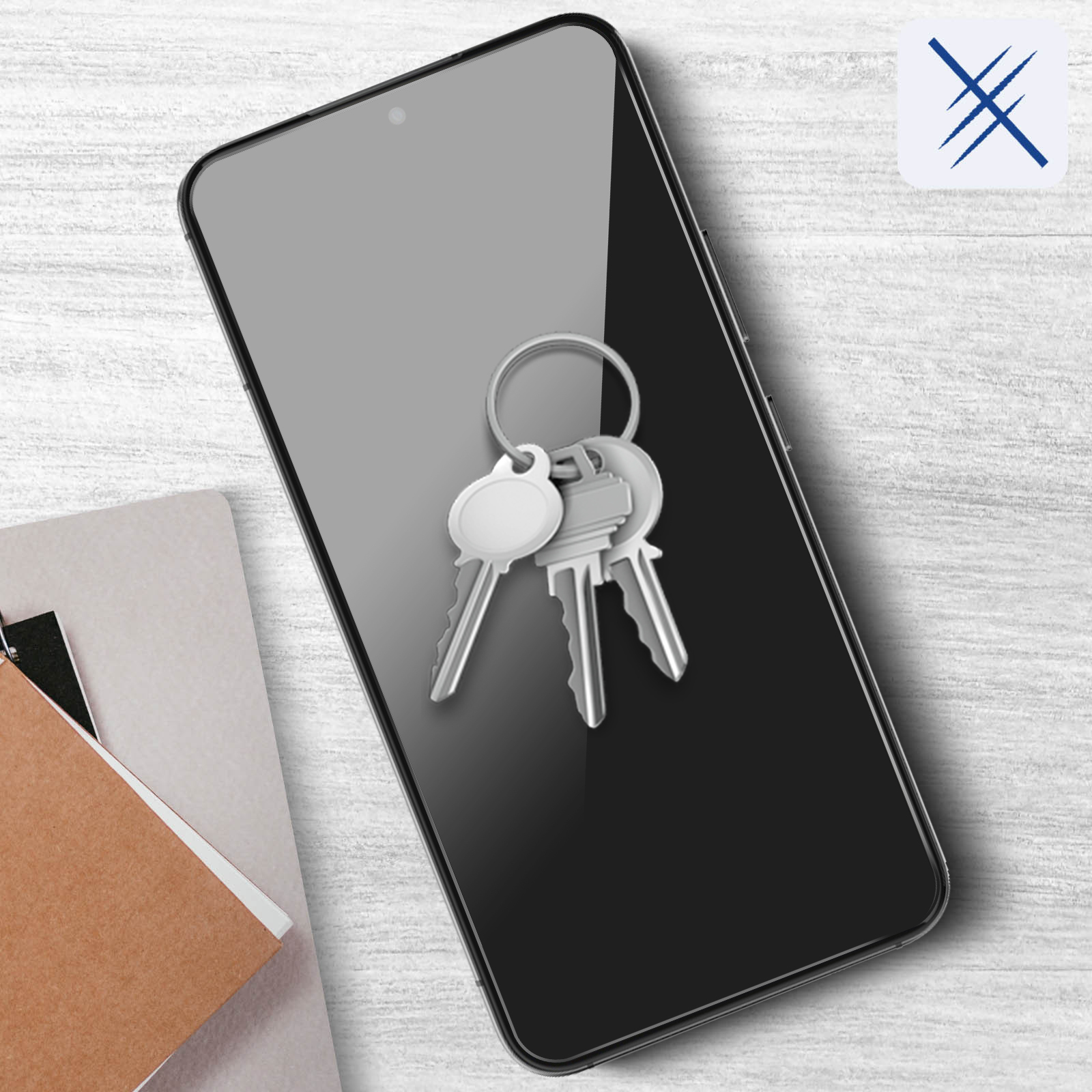 Klucze na telefonie z ochroną ekranu. Telefon leży na jasnej drewnianej powierzchni. Ikona w prawym górnym rogu.