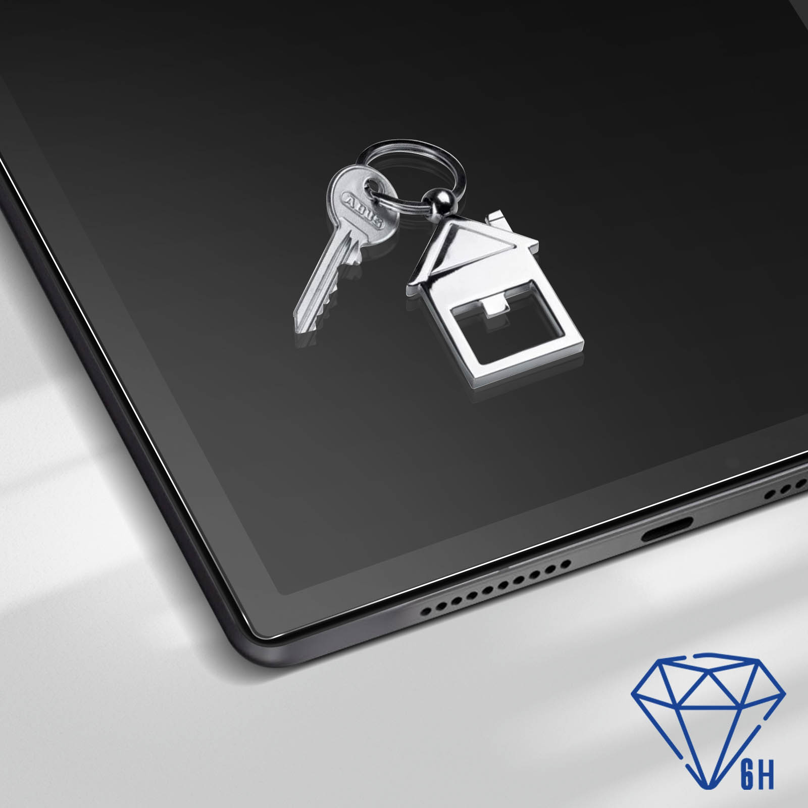 Klucze i brelok w kształcie domu na czarnym ekranie tabletu. Symbol diamentu 6H.