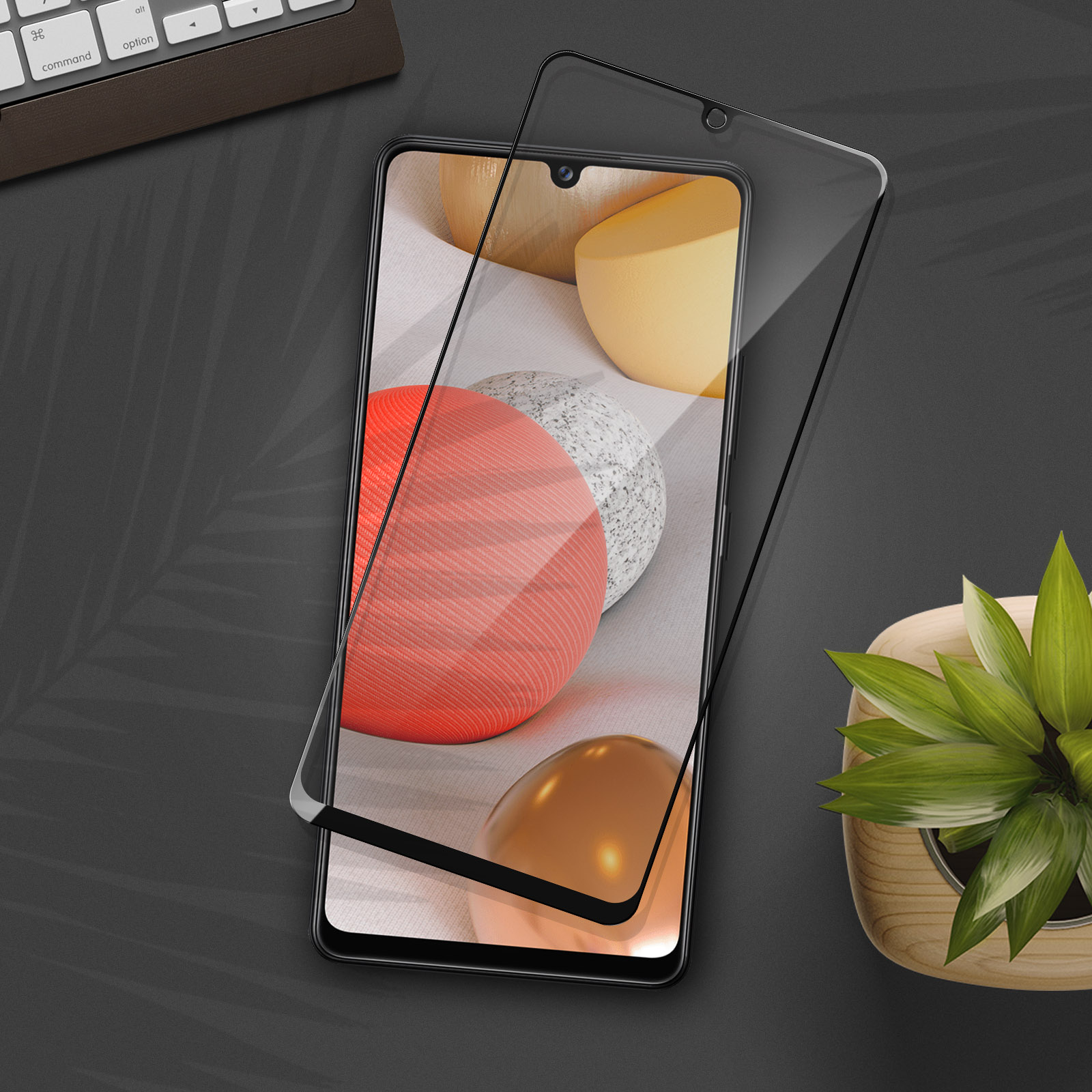 Un téléphone avec un protecteur d'écran par-dessus, sur une surface sombre avec des formes 3D en arrière-plan et une plante.