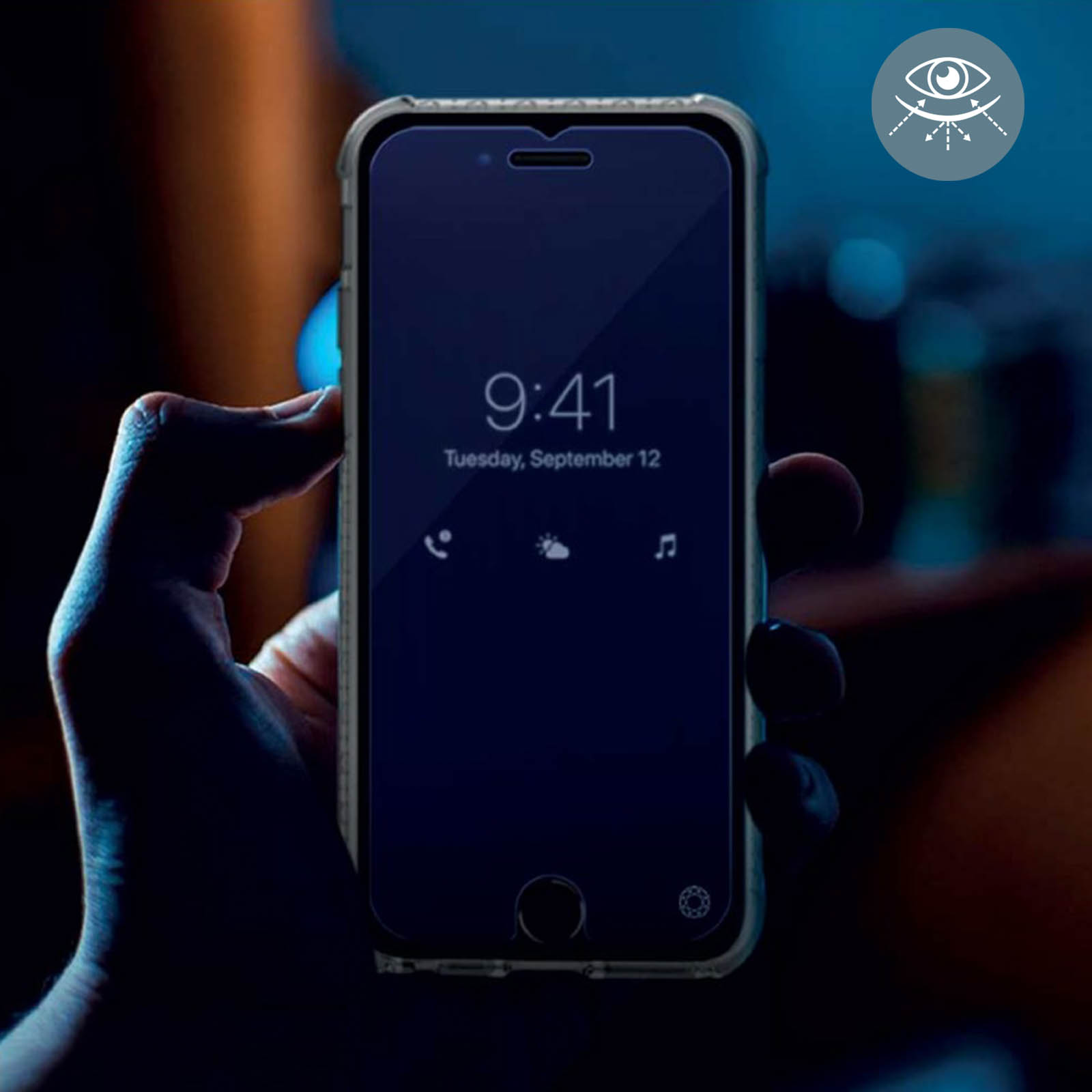 Une main tient un téléphone dont l'écran affiche l'heure et la date. Le fond est flou.