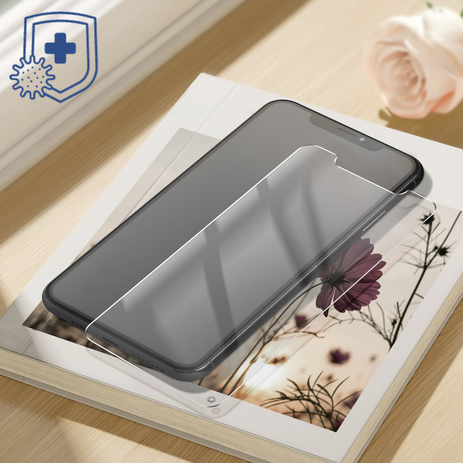 A phone with a screen protector on a book, with a flower. A shield with germs is shown.