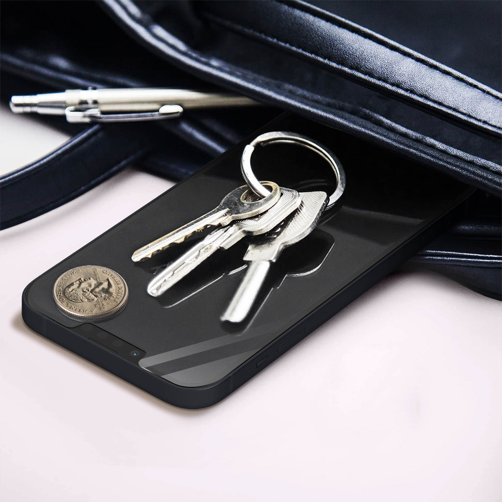 Chiavi e una moneta sullo schermo di un telefono all'interno di una borsa nera.