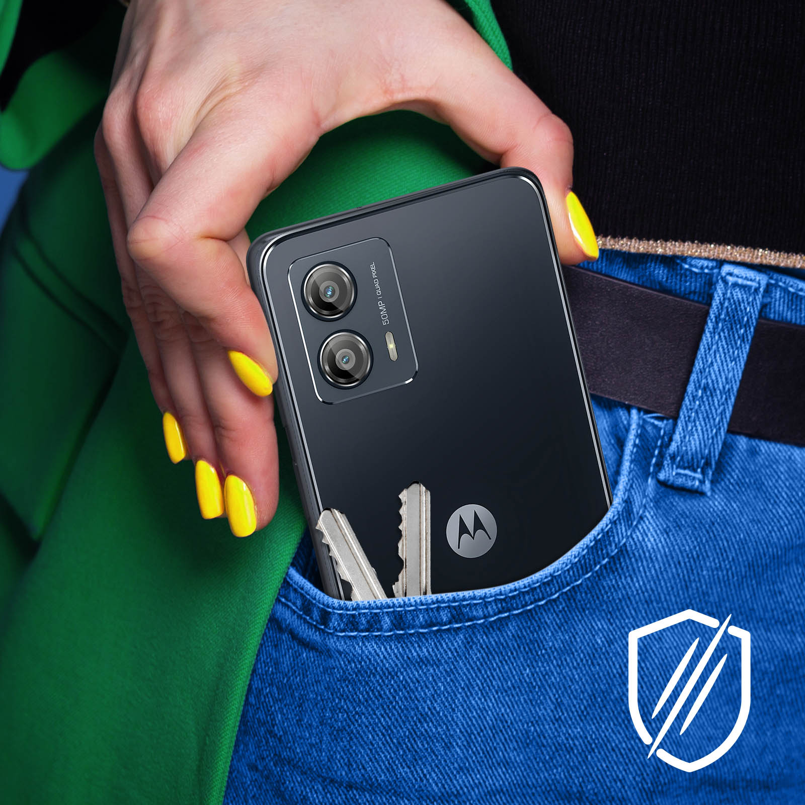 Una mano con uñas amarillas sostiene un teléfono, llaves en el bolsillo. El teléfono tiene dos cámaras y un logo Motorola en jeans azules.