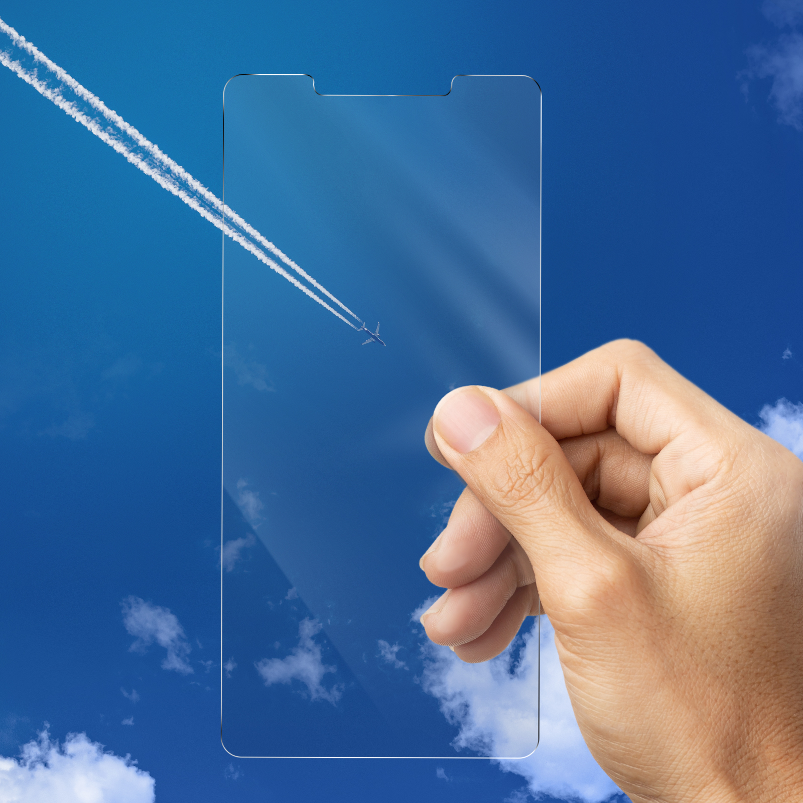 Una mano che tiene una protezione schermo trasparente contro un cielo blu con aereo e scie di condensa.