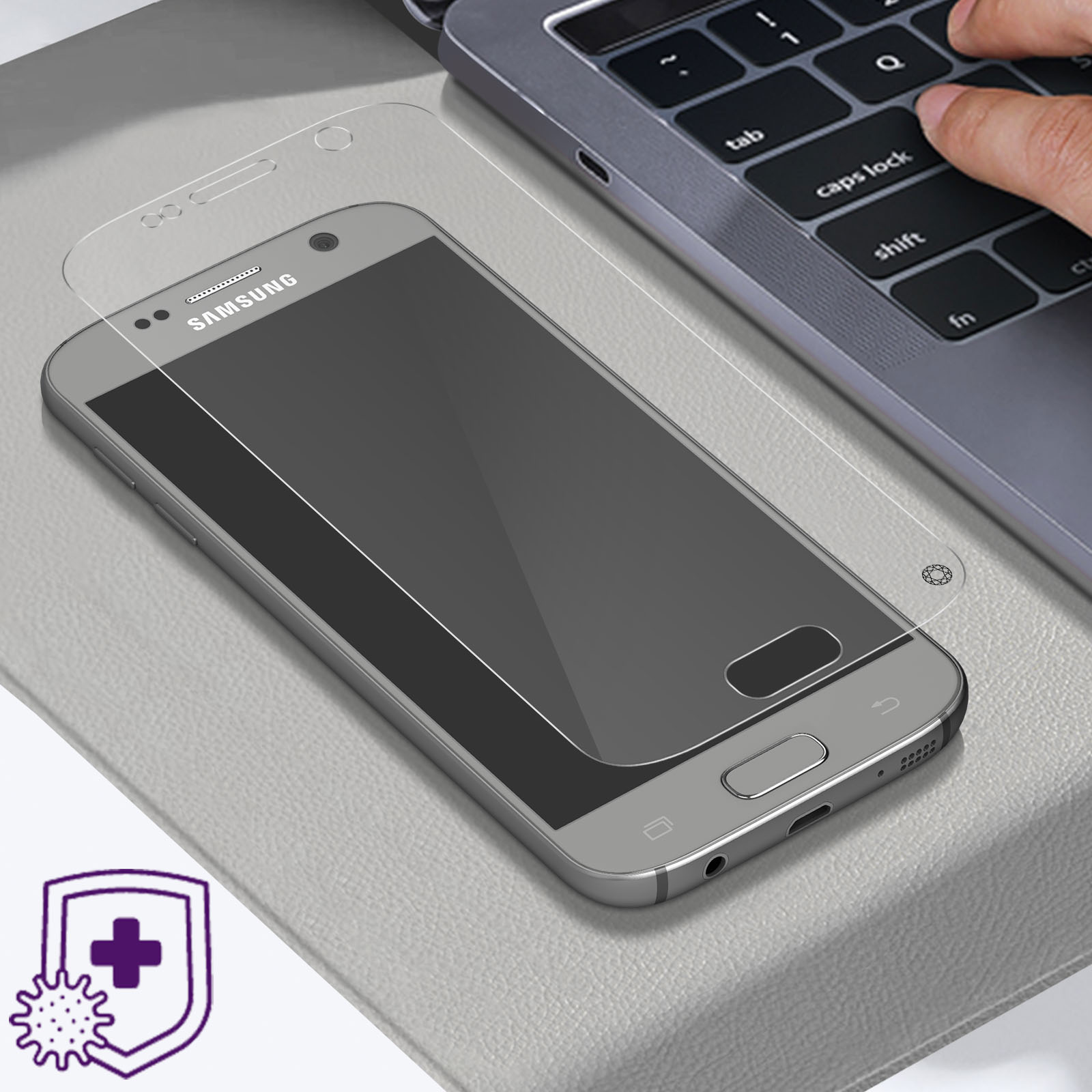 Un telefono con proteggi schermo e un laptop su una scrivania, mano che tocca la tastiera.