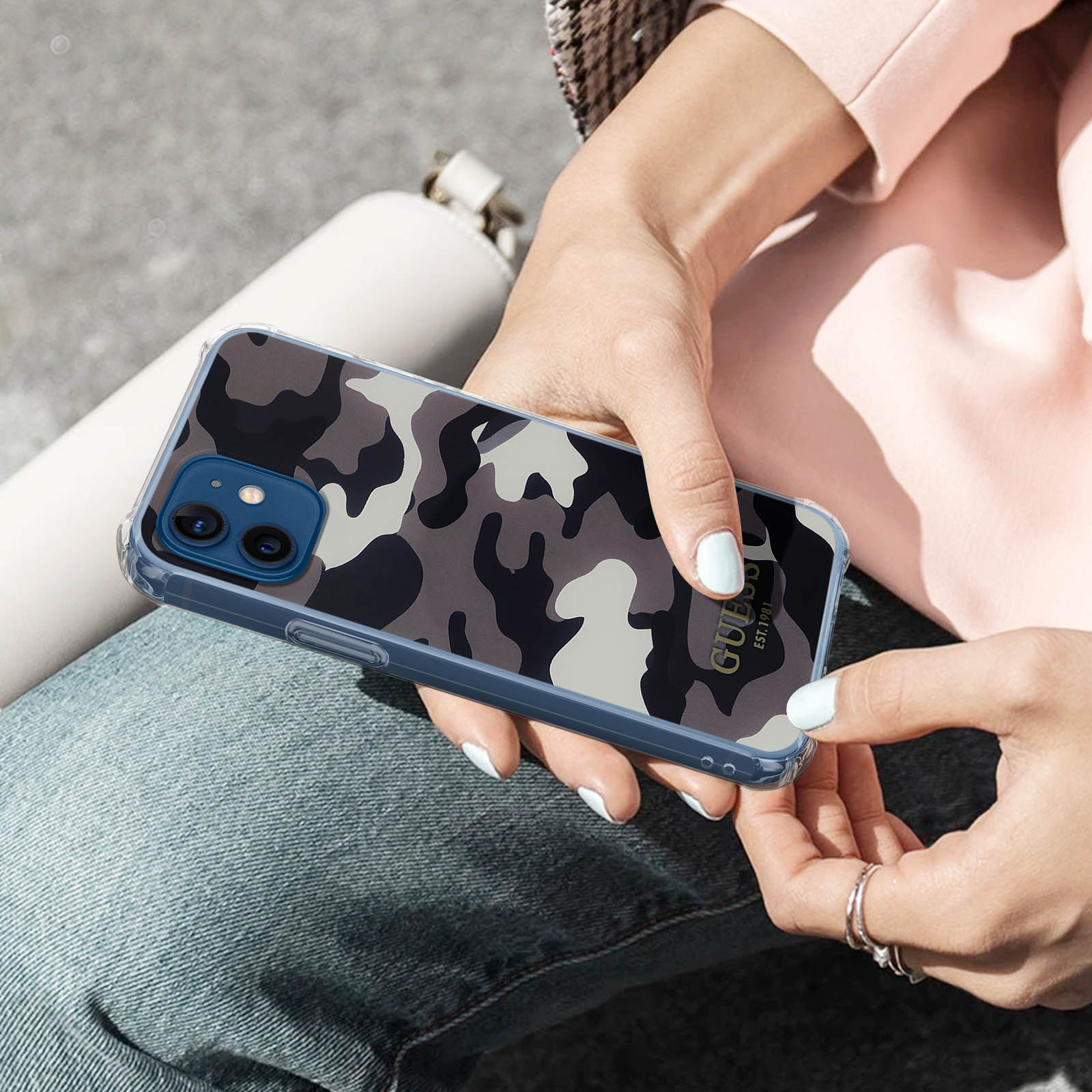 Eine Person hält ein Telefon in einer transparenten Tarnhülle. Die Frau trägt ein rosa Oberteil und Jeans.