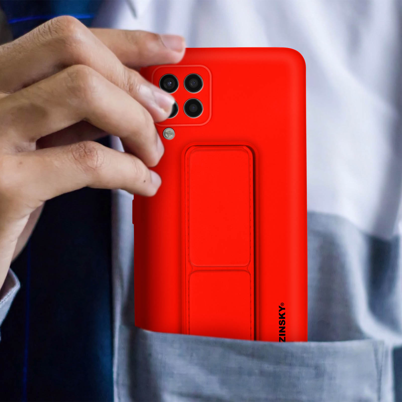 Czerwone etui na telefon z podpórką w czyjejś kieszeni.