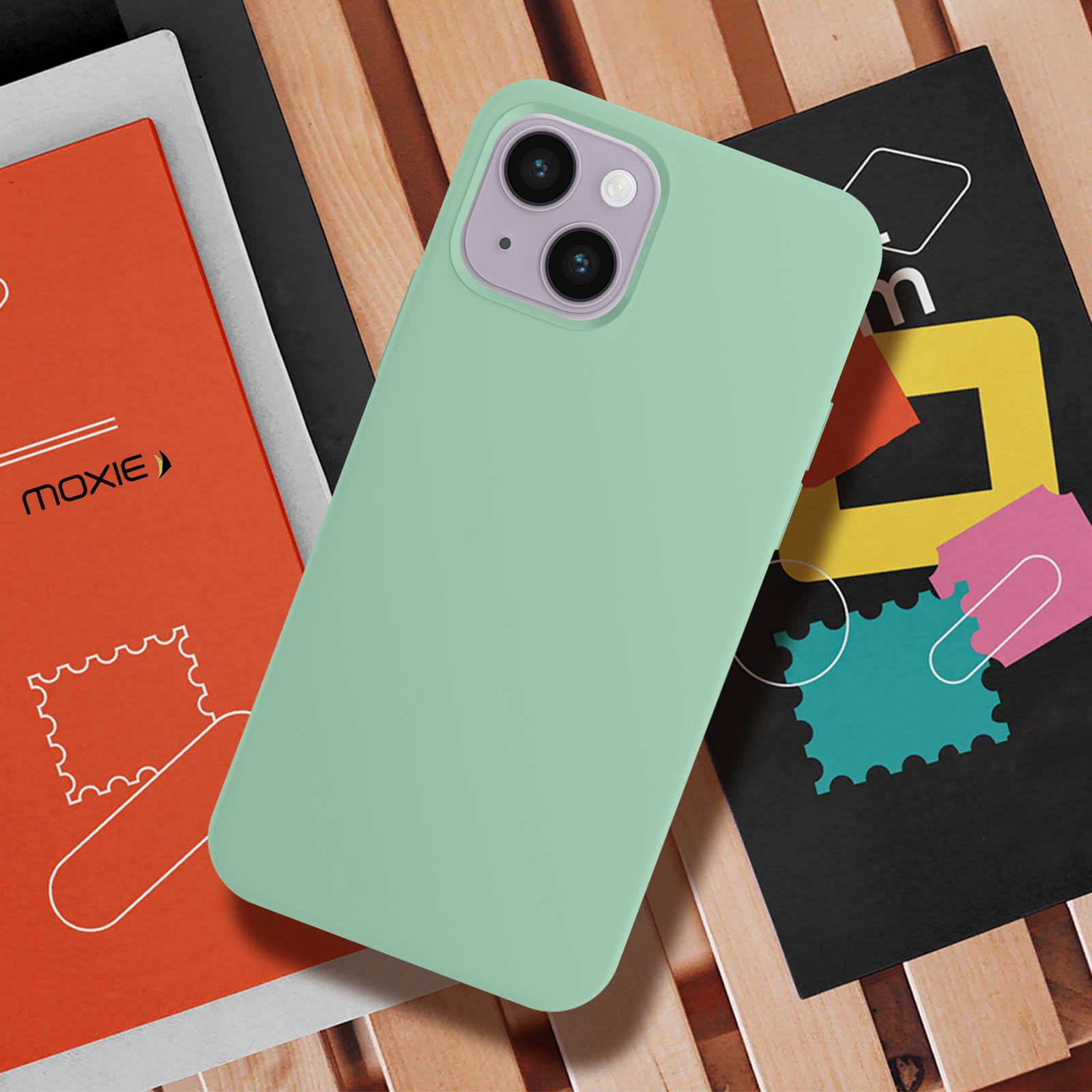 Mintgroene telefoonhoes met paarse camera, rustend op boeken en hout.