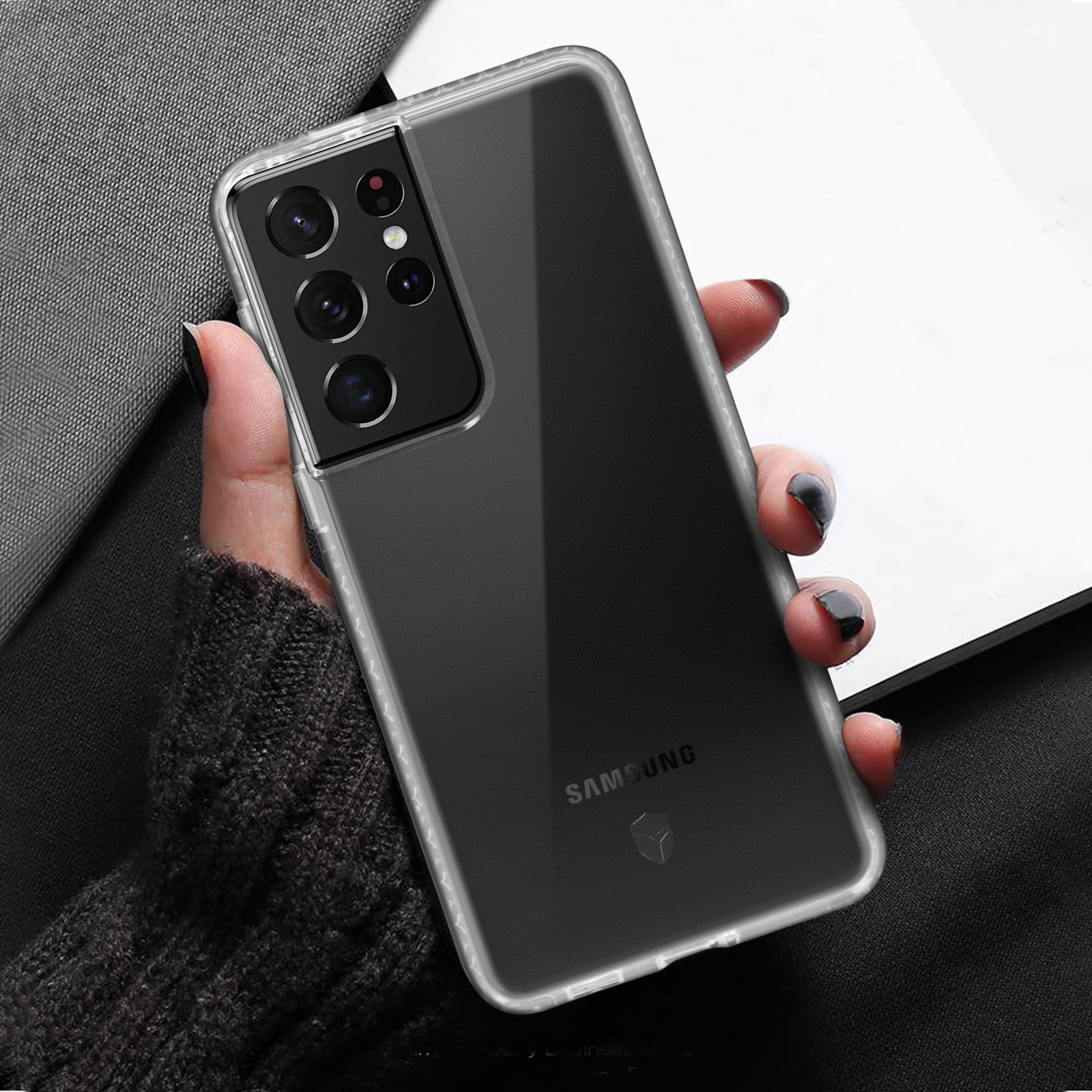 Hand hält eine transparente Handyhülle mit einem Telefon darin. Samsung-Logo sichtbar.
