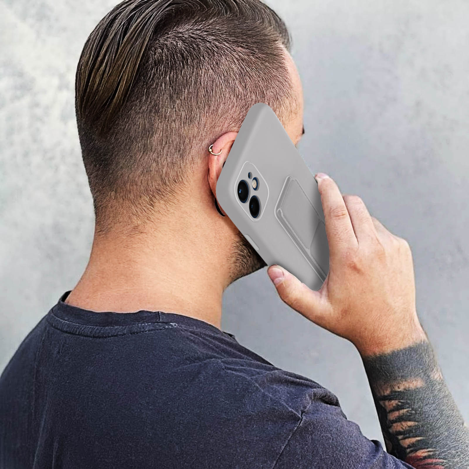 Un uomo che tiene un telefono all'orecchio. Il telefono è in una custodia grigia.