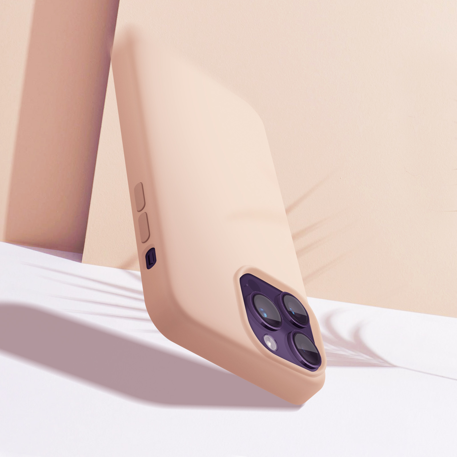 Een beige telefoonhoesje leunt tegen een muur met een schaduw, met de cameralenzen zichtbaar.