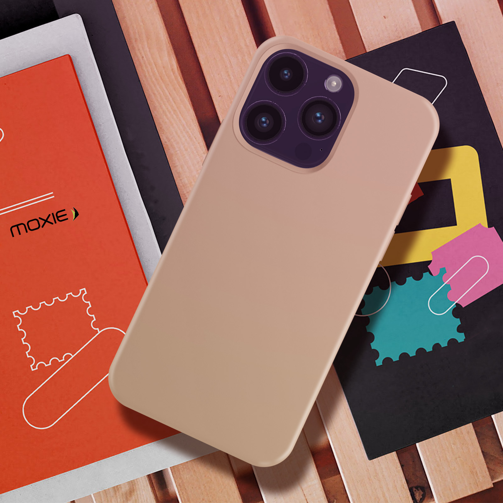 Een telefoon met een beige hoesje ligt op boeken en een kleurrijke poster.