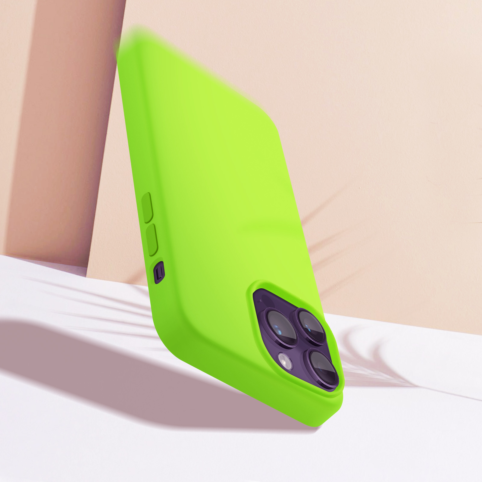 Coque de téléphone verte appuyée contre une surface blanche. Trois objectifs d'appareil photo sont visibles.
