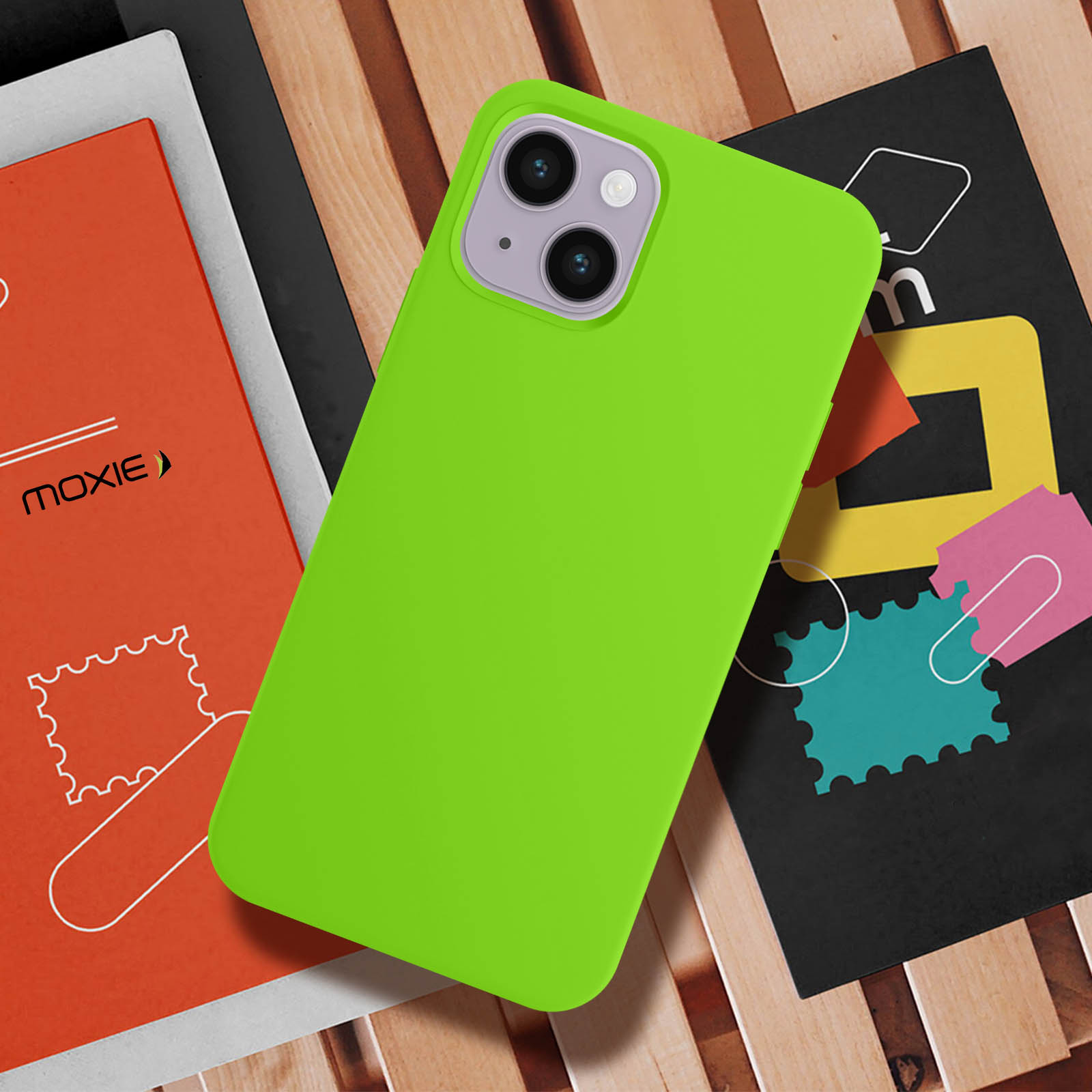 Une coque de téléphone vert citron sur bois, avec livres et autocollants colorés.
