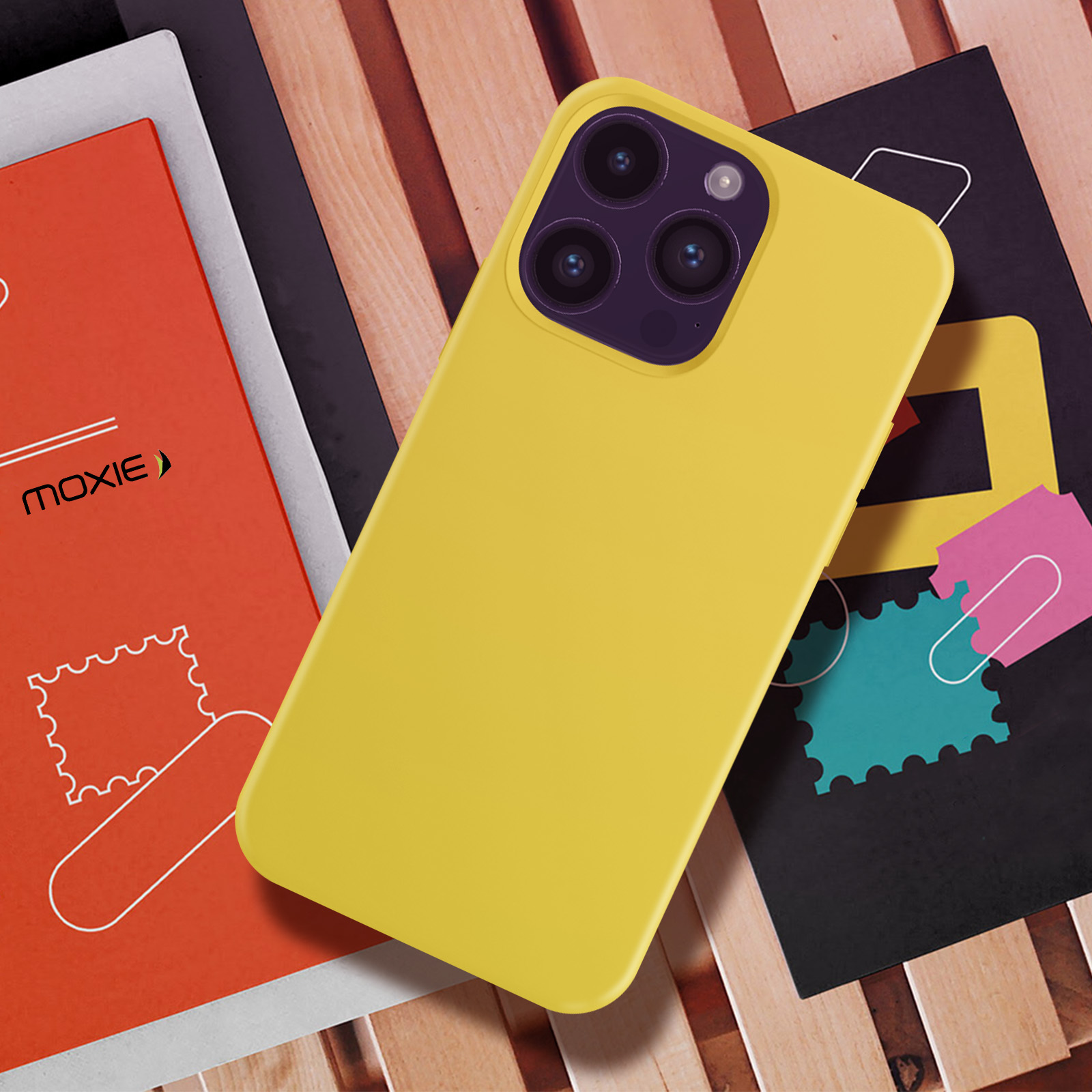 Une coque de téléphone jaune sur du bois avec des livres et des graphiques colorés en arrière-plan.