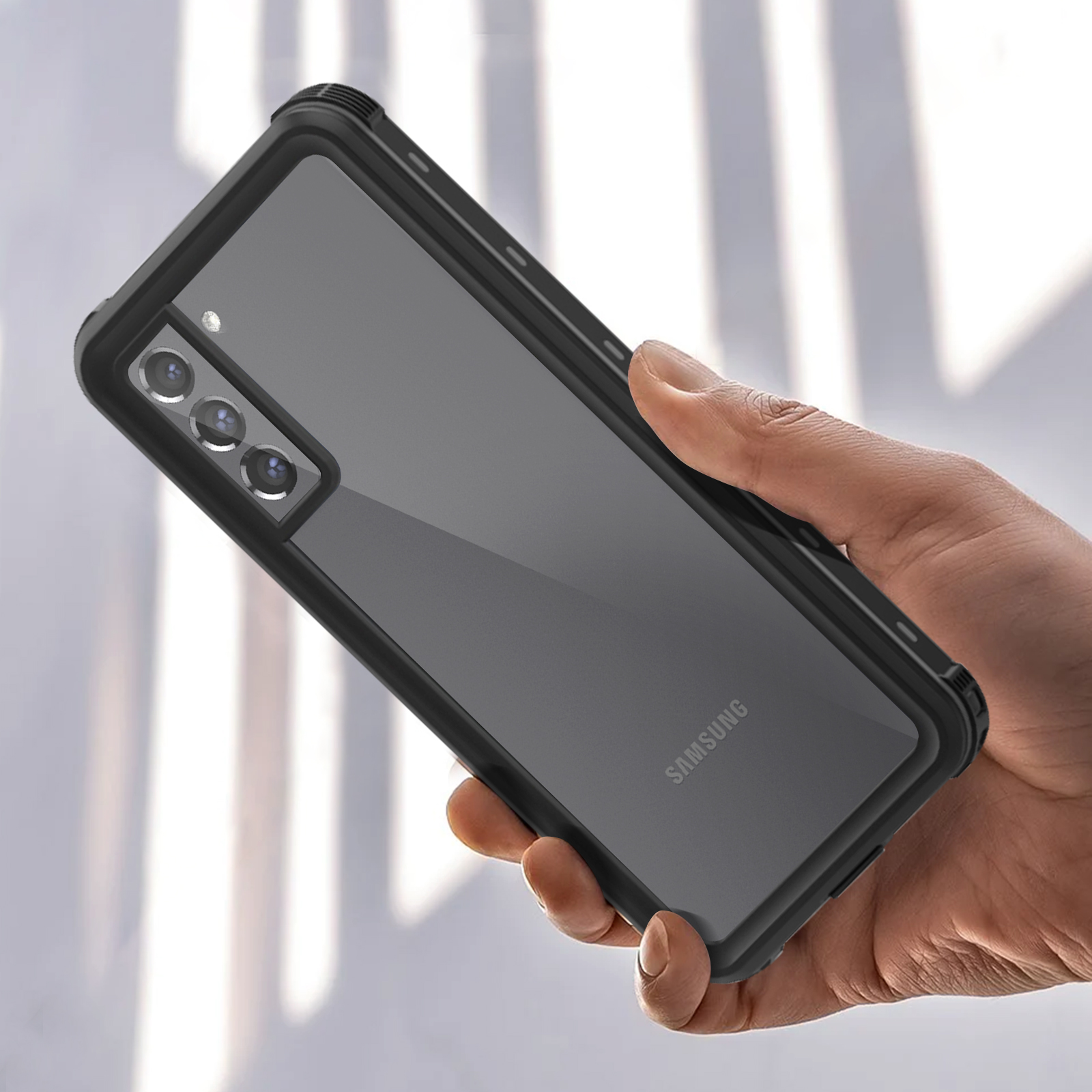 Hand hält schwarzes Telefon in klarer Hülle mit Dreifachkamera.