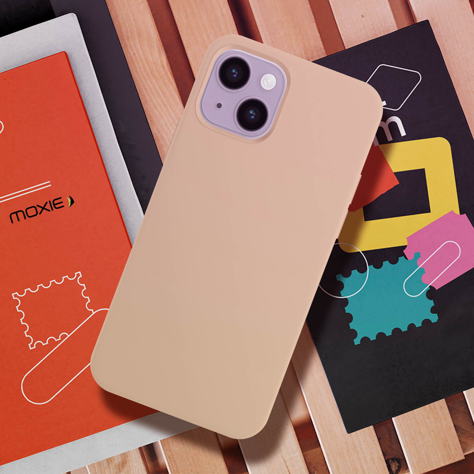 Coque de téléphone posée sur des livres, avec un dessus rose et un dos beige.