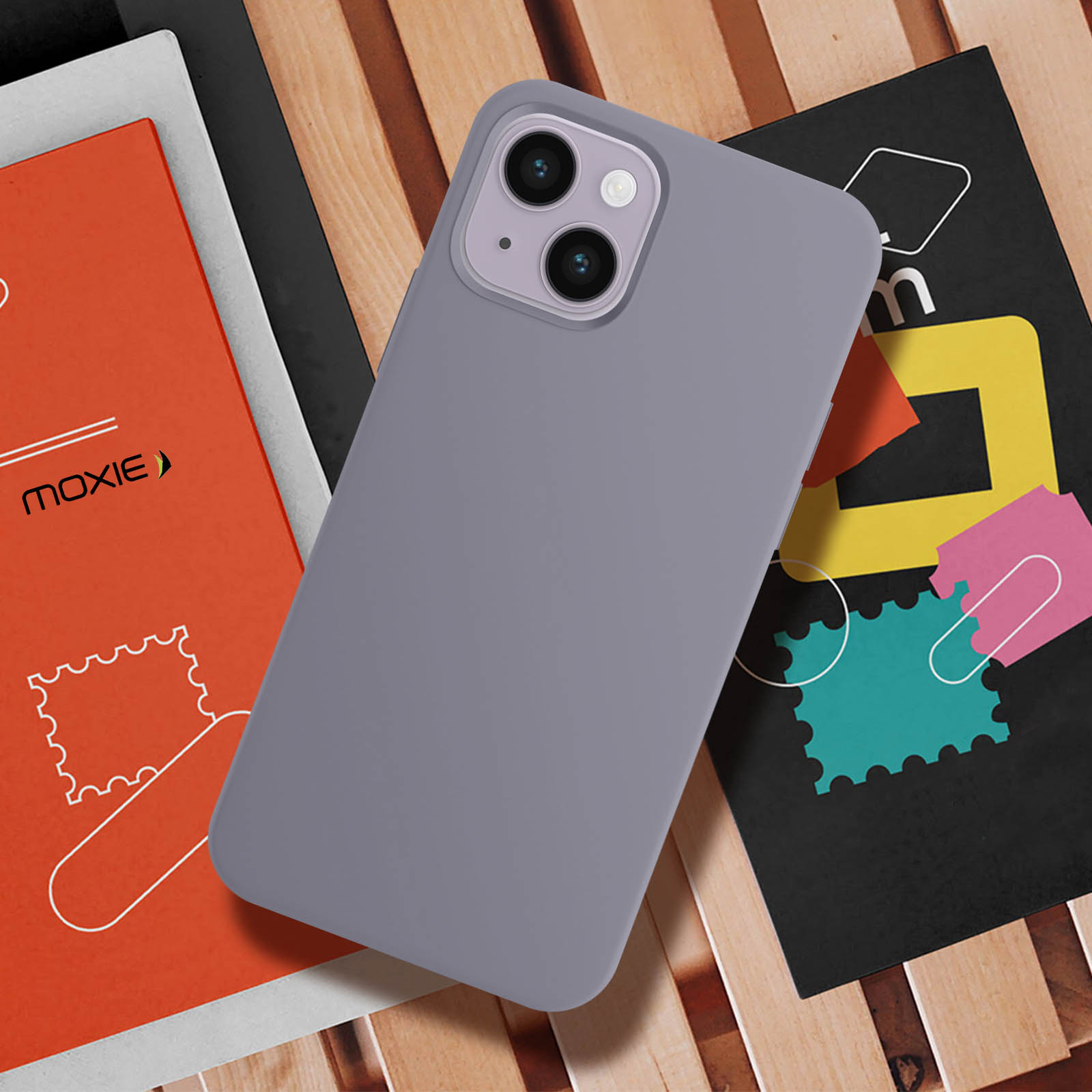 Paarse telefoonhoes op een houten oppervlak met boeken en kleurrijke stempelachtige afbeeldingen.