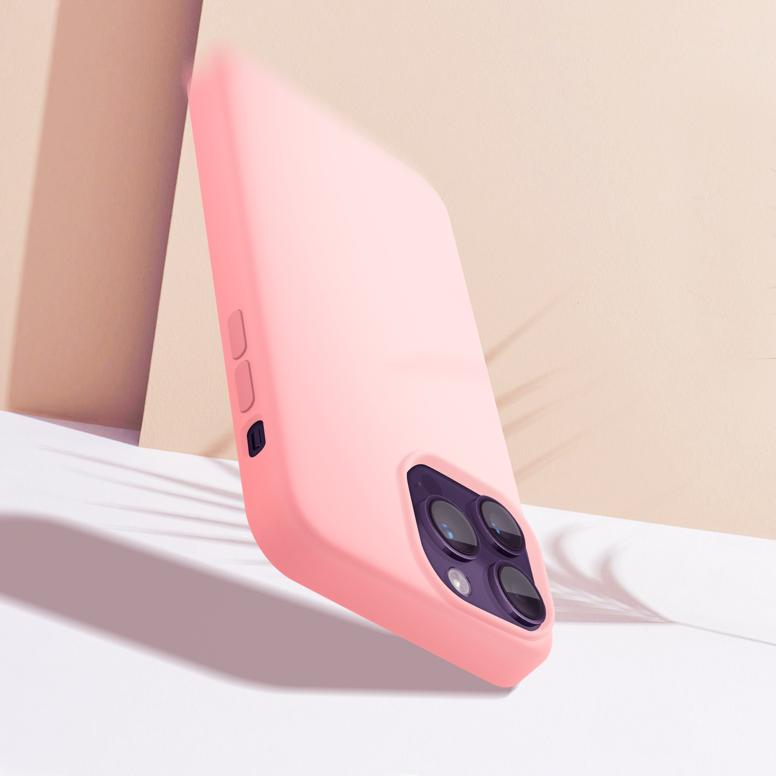 Roze telefoonhoes staat schuin tegen crème achtergrond, toont cameradetails.