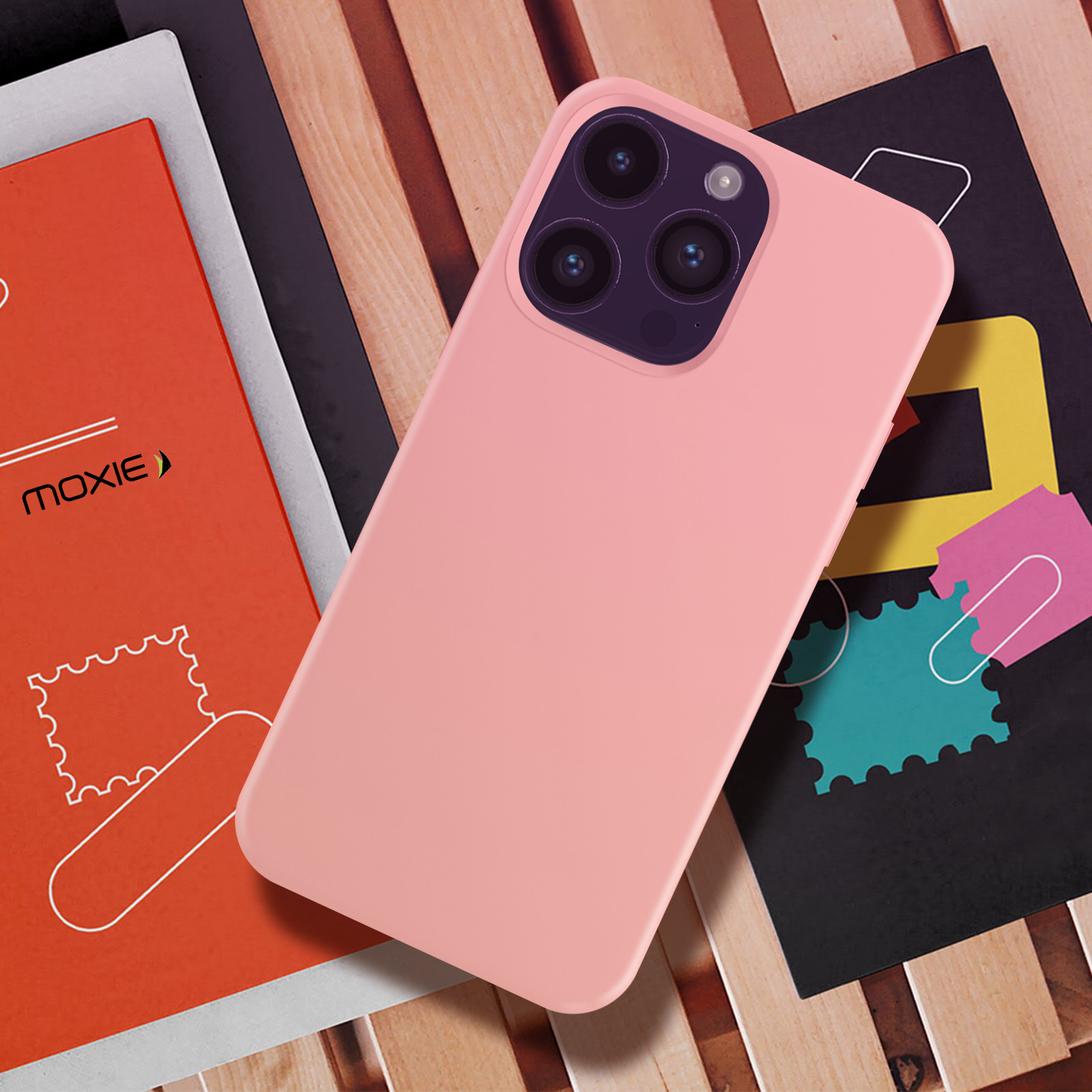 Roze telefoonhoes op houten oppervlak, met boeken en roze telefoon.