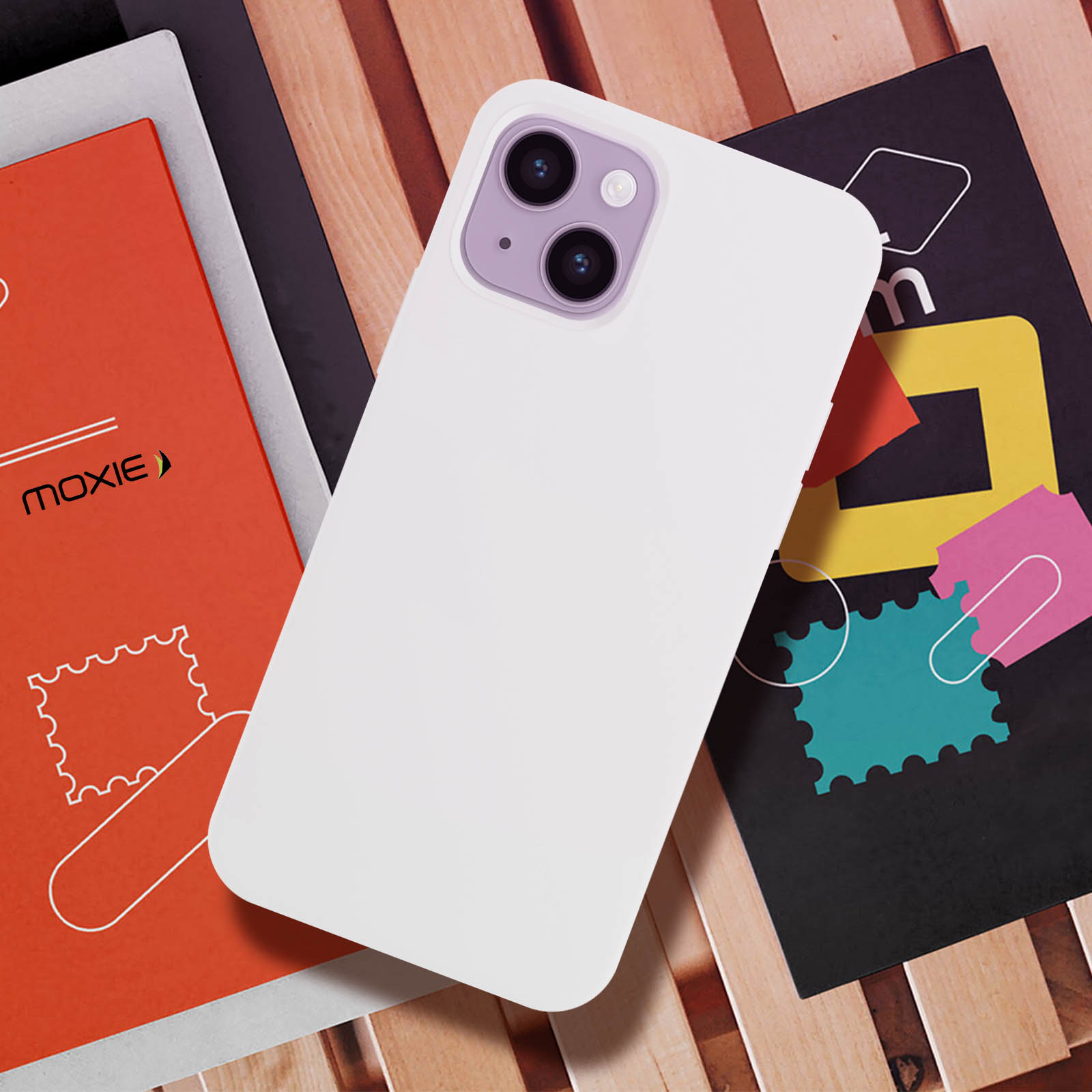 Een witte telefoonhoes met een paarse camera-omgeving. Het ligt op hout met twee tijdschriften.
