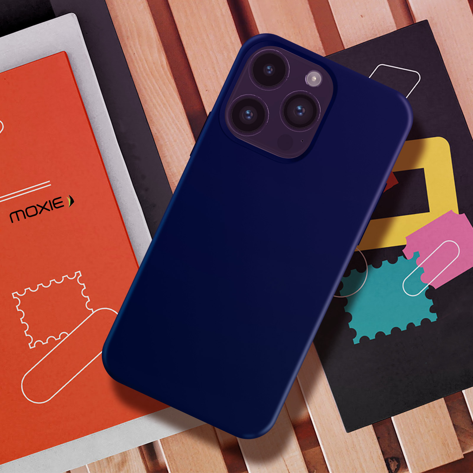 Une coque de téléphone bleu marine sur une surface en bois avec des livres. Le téléphone a une bosse pour la caméra.