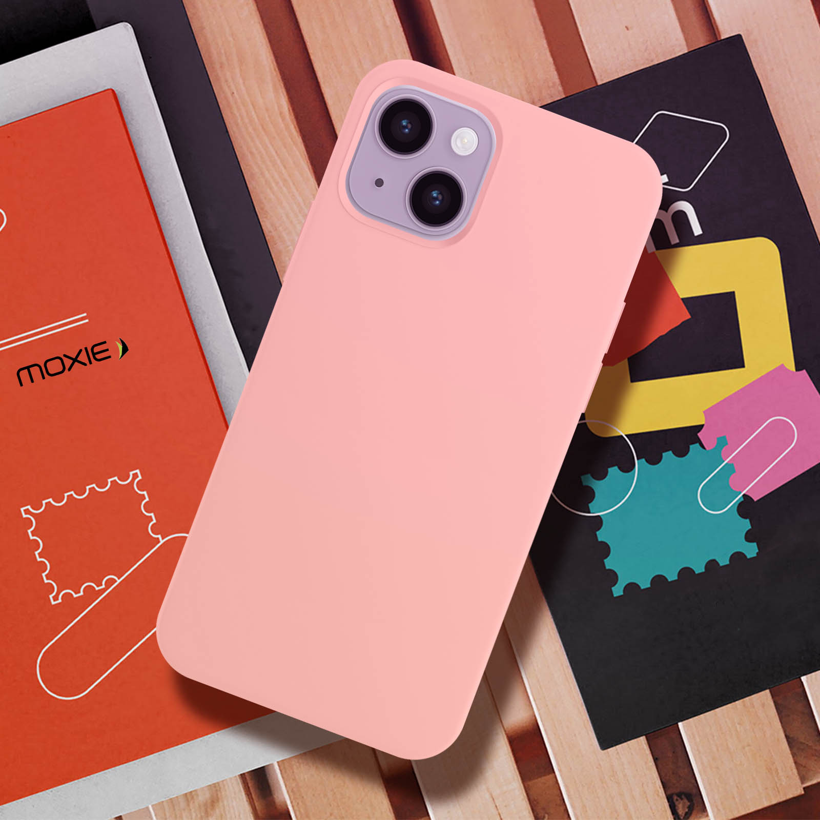 Un téléphone rose avec un appareil photo violet, posé sur des livres et des magazines.