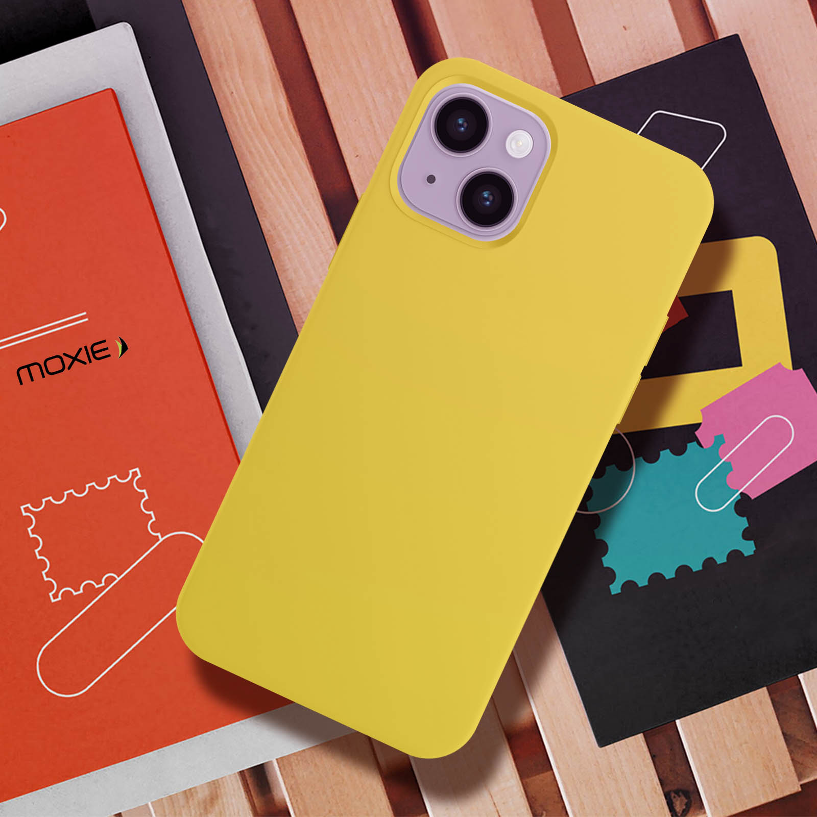 Een gele telefoonhoes op een telefoon. De telefoon ligt op boeken en ansichtkaarten.