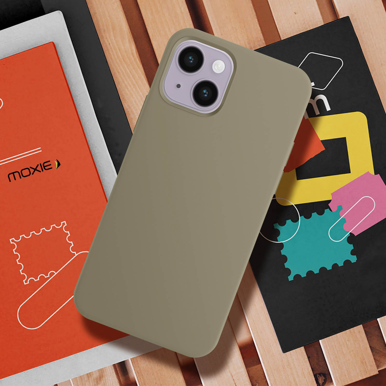 Een telefoon in een bruine hoes op een tafel met boeken en andere voorwerpen.