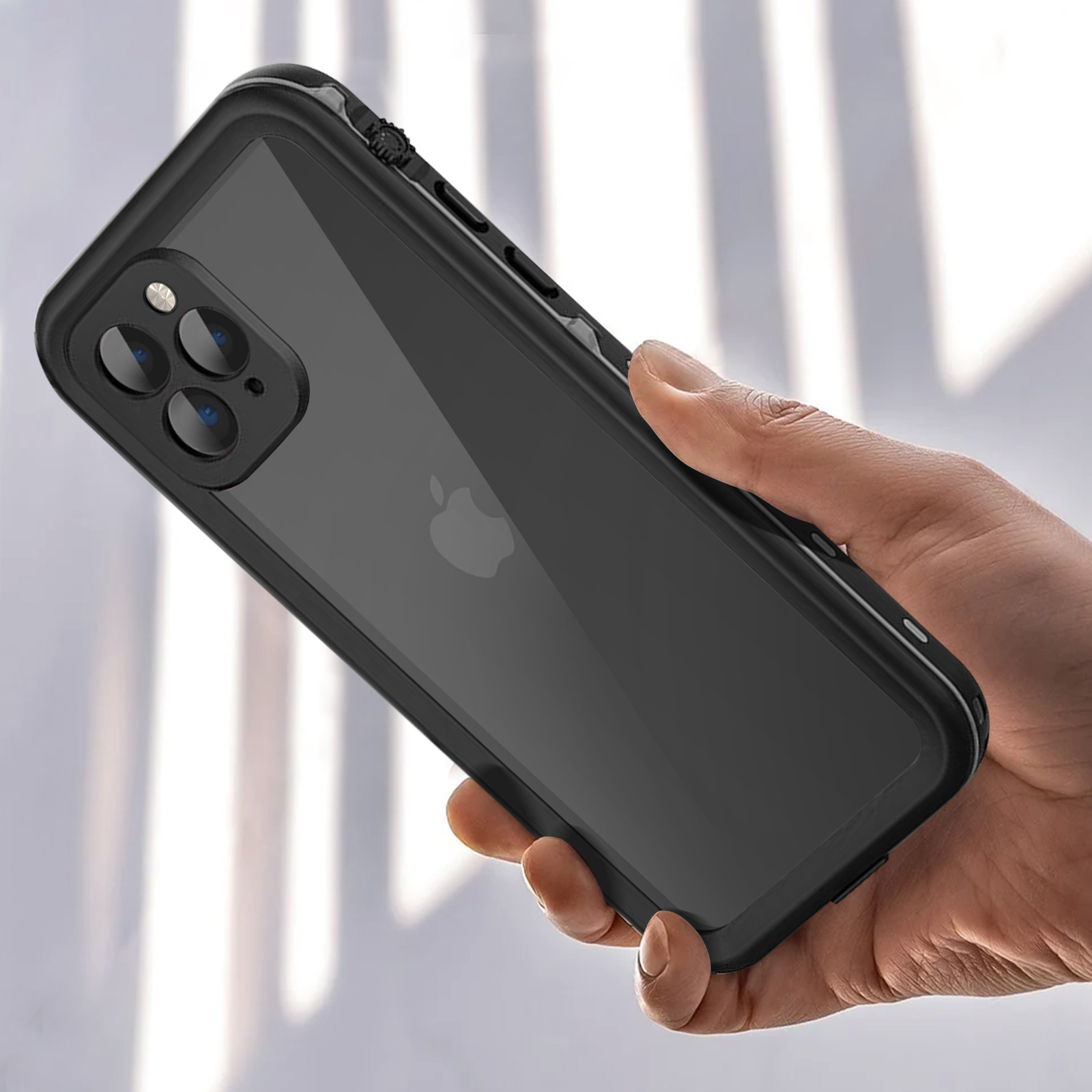 La mano di una persona che tiene un telefono nero con una custodia trasparente. La custodia ha un rigonfiamento della fotocamera con tre lenti.