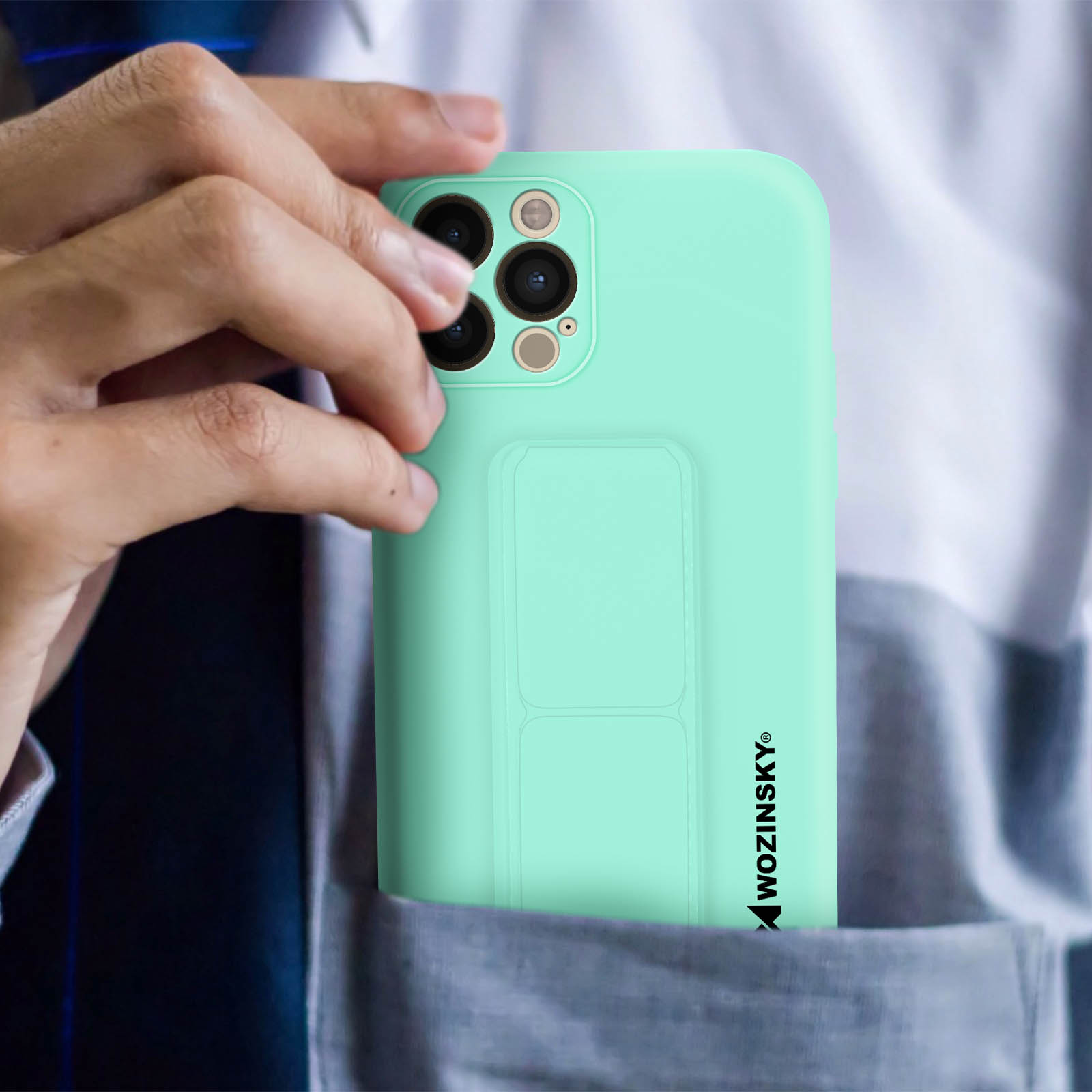 Ręka trzyma miętowy zielony pokrowiec na telefon w kieszeni. Pokrowiec zakrywa większość telefonu.