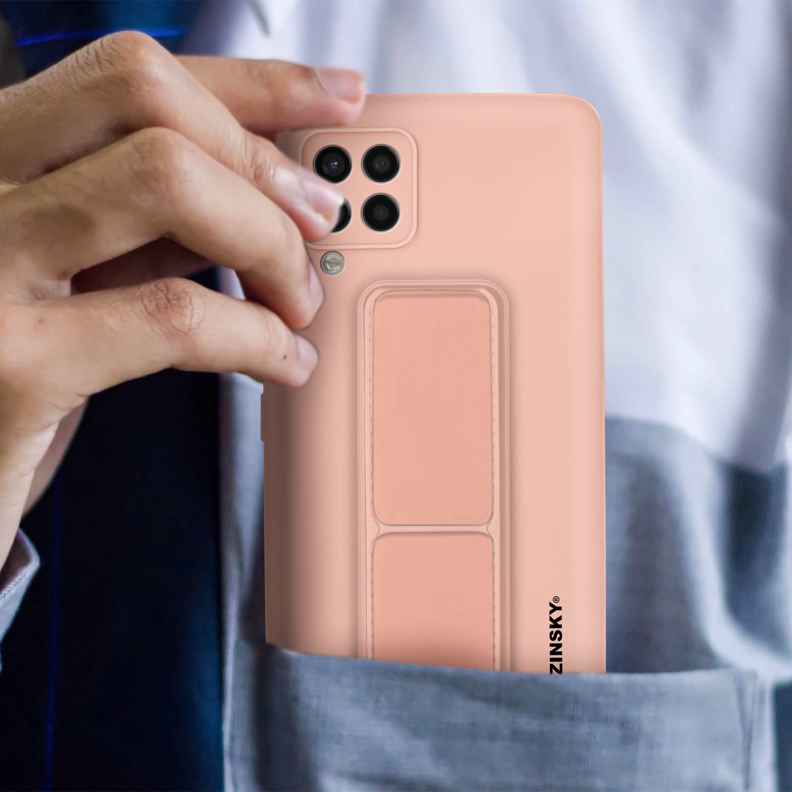 Ręka w kieszeni trzymająca różowe etui z dołączonym paskiem.