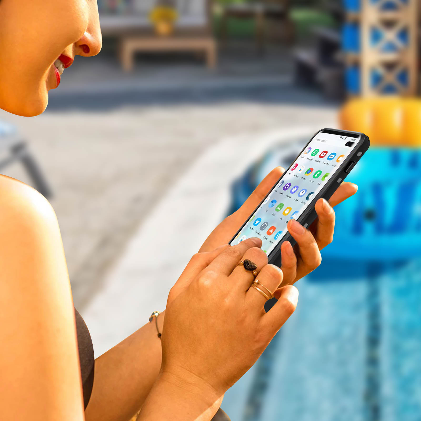 Una donna usa un telefono. È vicino a una piscina e lo schermo mostra icone di app.