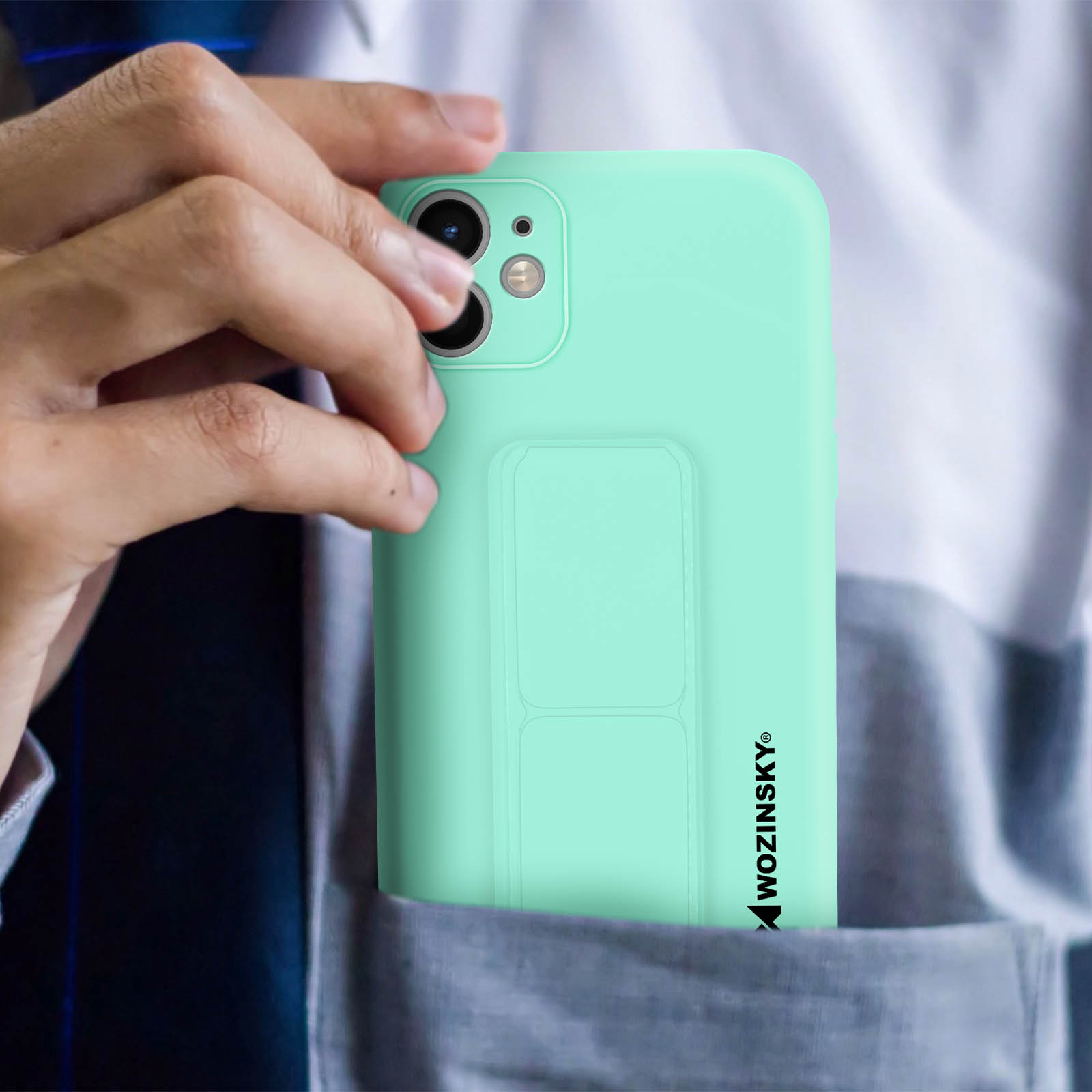 Ręka wkłada telefon do kieszeni. Telefon jest w jasnoniebieskim etui z uchwytem.