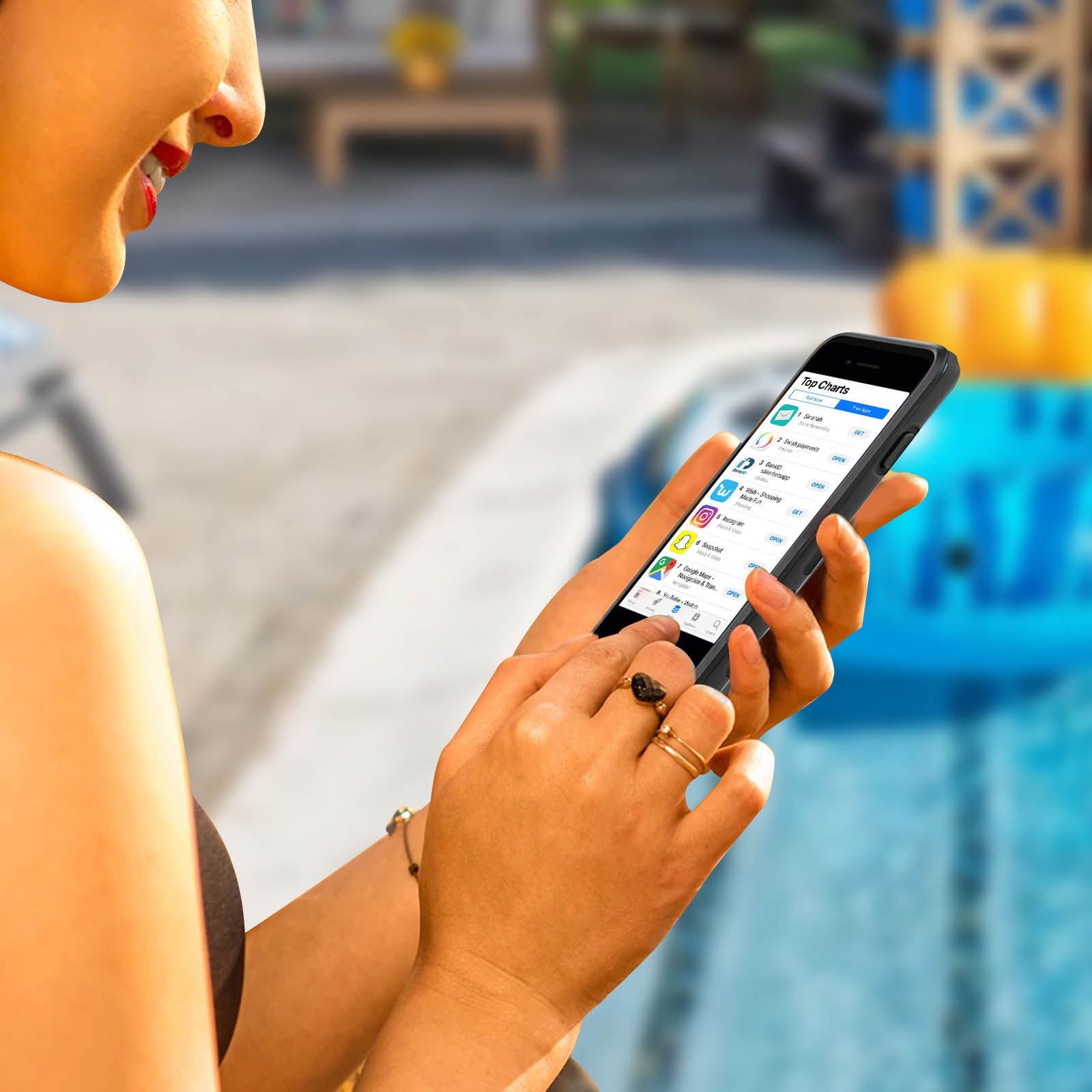 Donna usa telefono nero, piscina sullo sfondo.