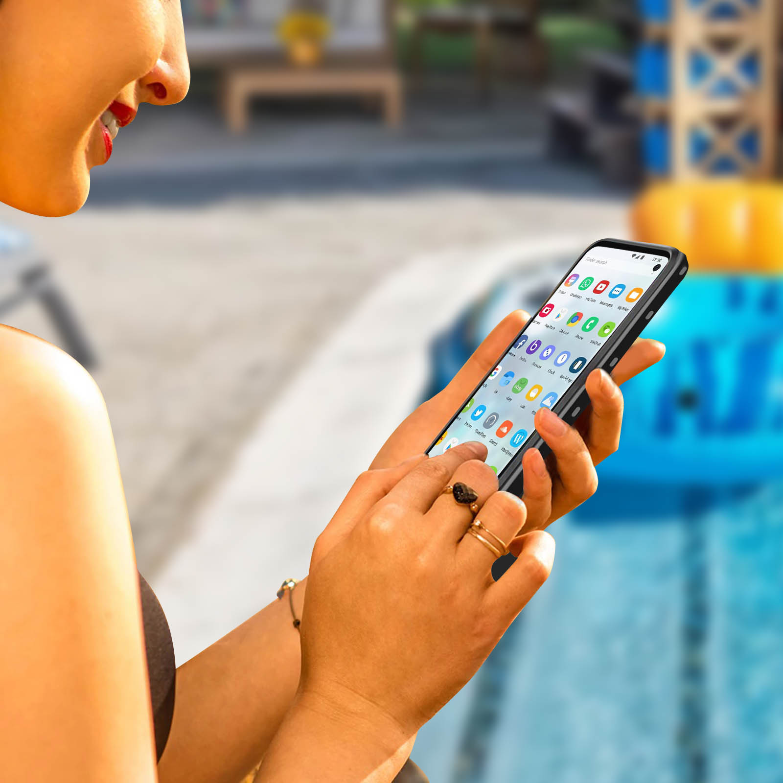Una donna con rossetto rosso usa un telefono con custodia nera. Una piscina sullo sfondo.