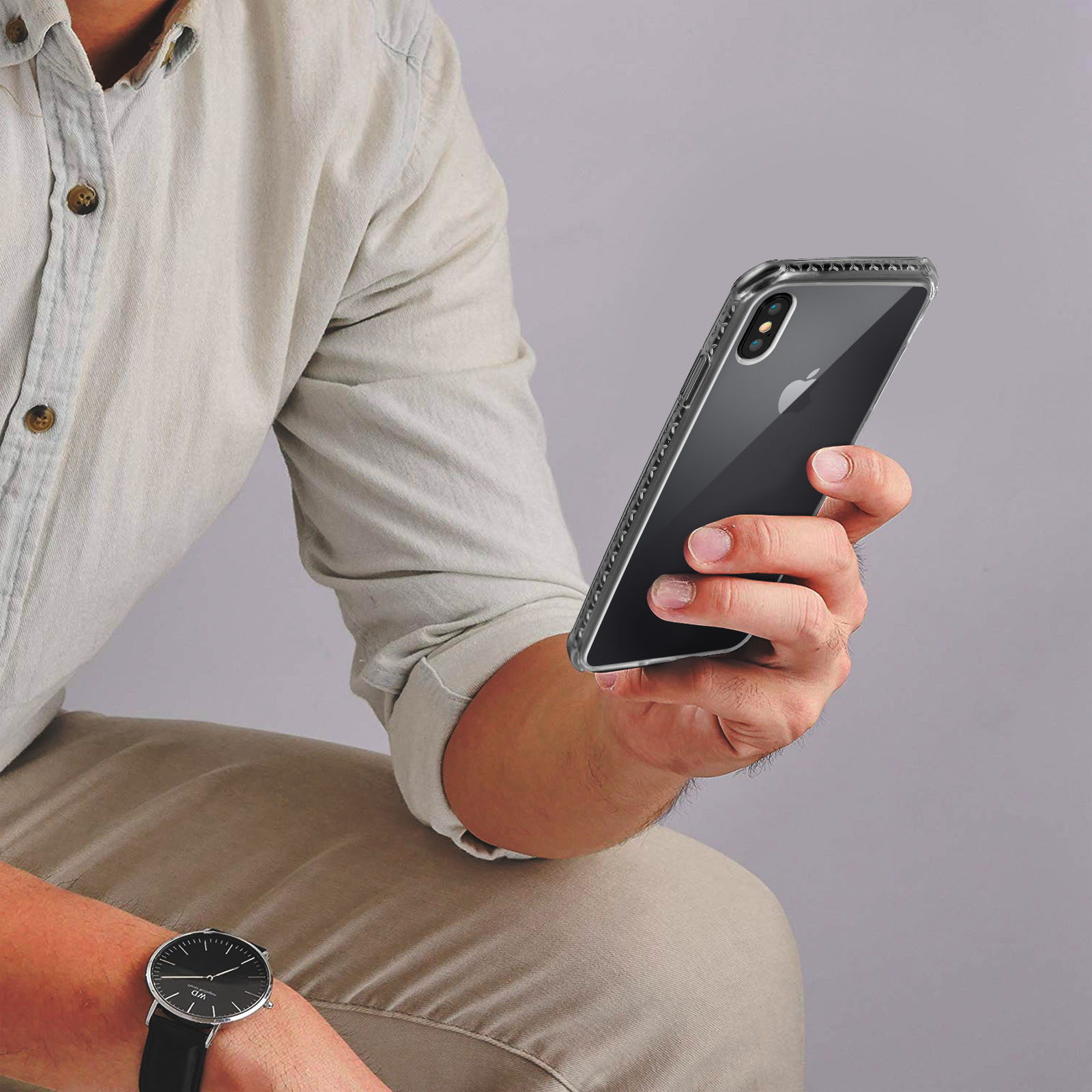 Uomo che tiene un telefono in una custodia trasparente, seduto, orologio al polso.
