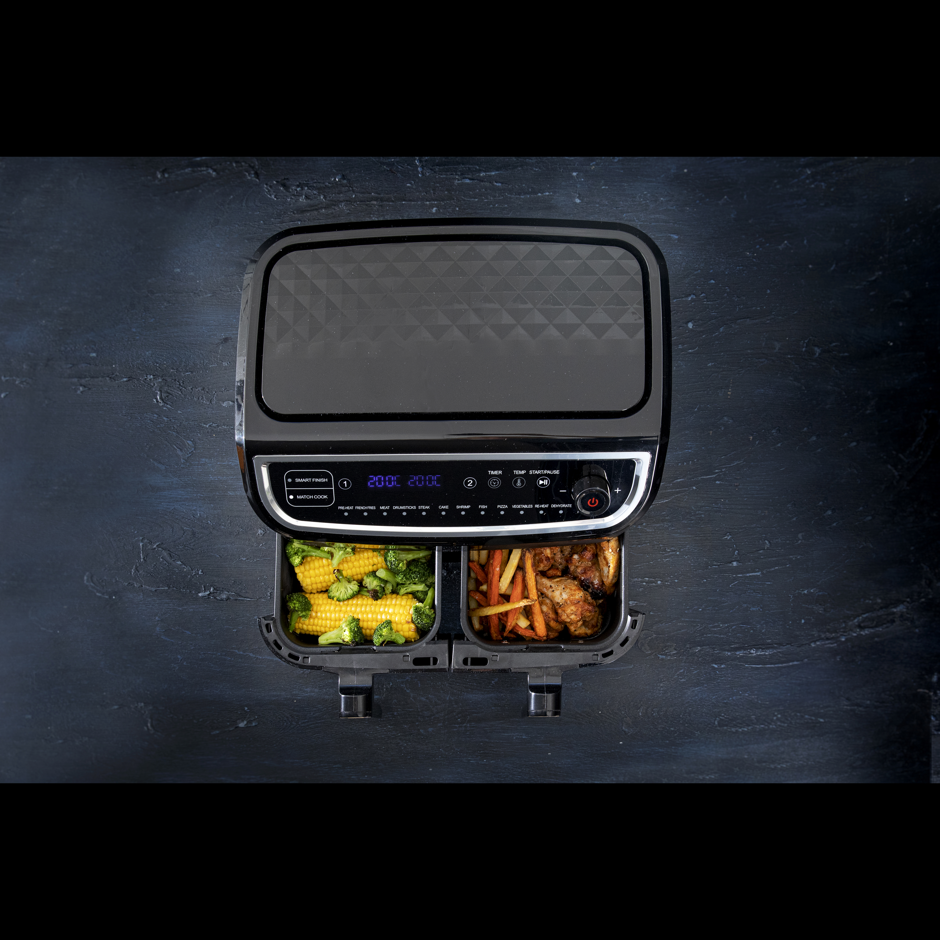 Czarna frytkownica powietrzna z przegrodami na żywność, kukurydzą, frytkami i kurczakiem.