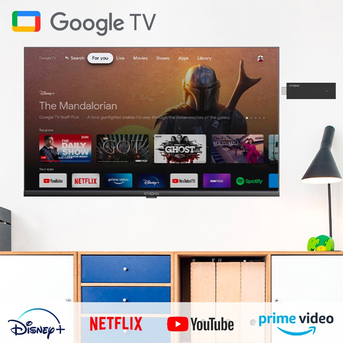 Google TV auf einem Fernsehbildschirm. Zeigt die Benutzeroberfläche mit Optionen wie Netflix, YouTube und Prime Video. Ein Stick daneben.
