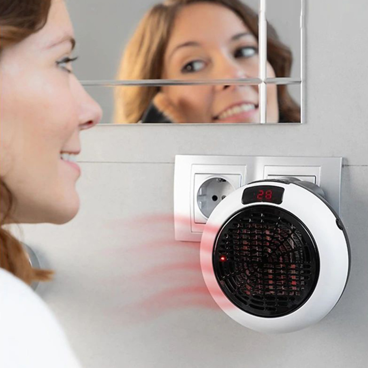 Una mujer mira un calefactor de pared, que muestra la temperatura. Un espejo está en el fondo.