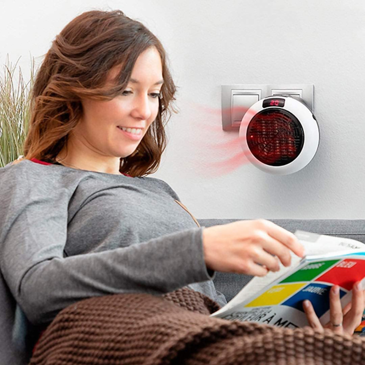 Mujer lee revista en sofá. Un calentador de pared está en la pared.